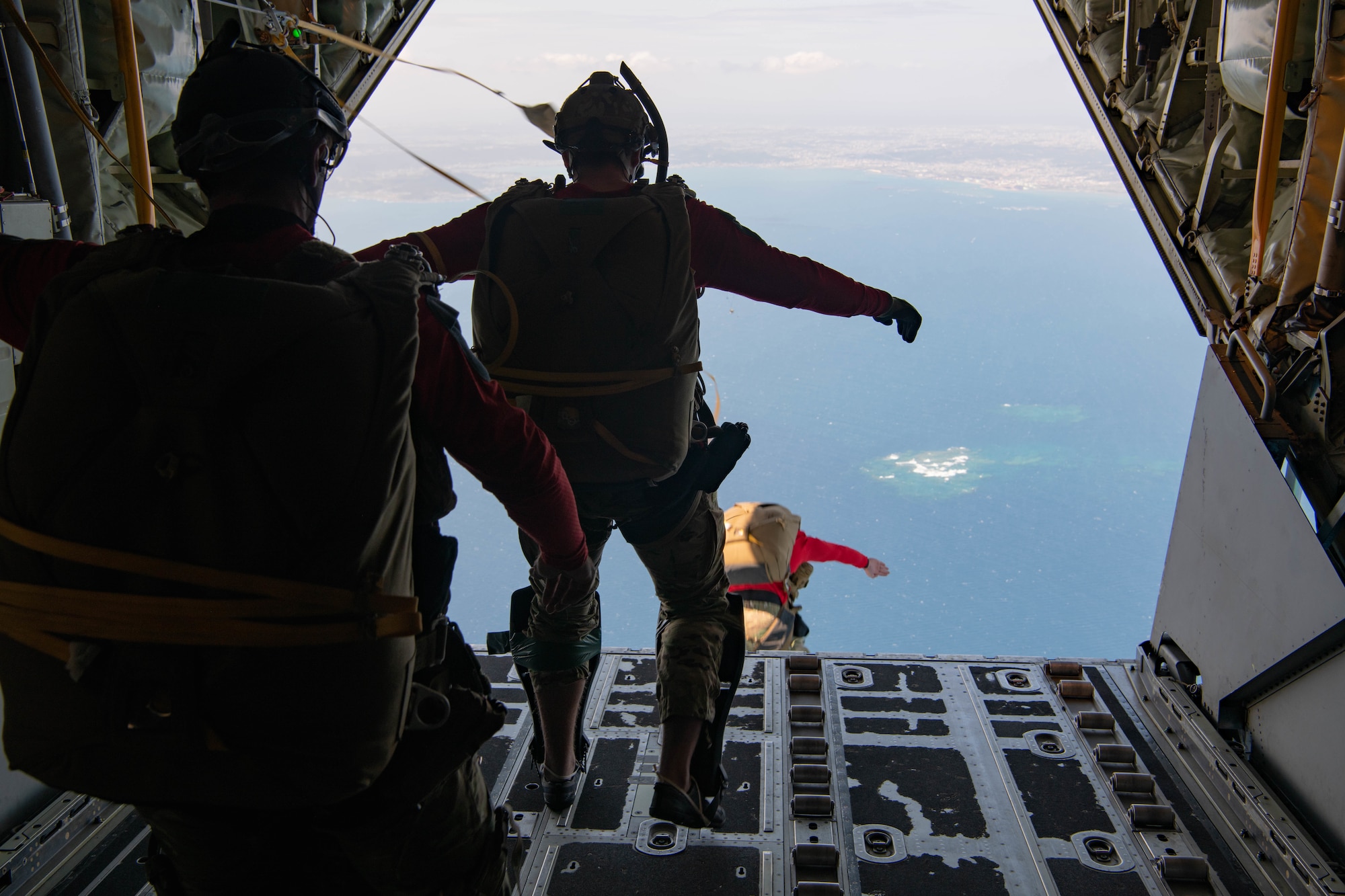 Airmen jump out of an aircraft.