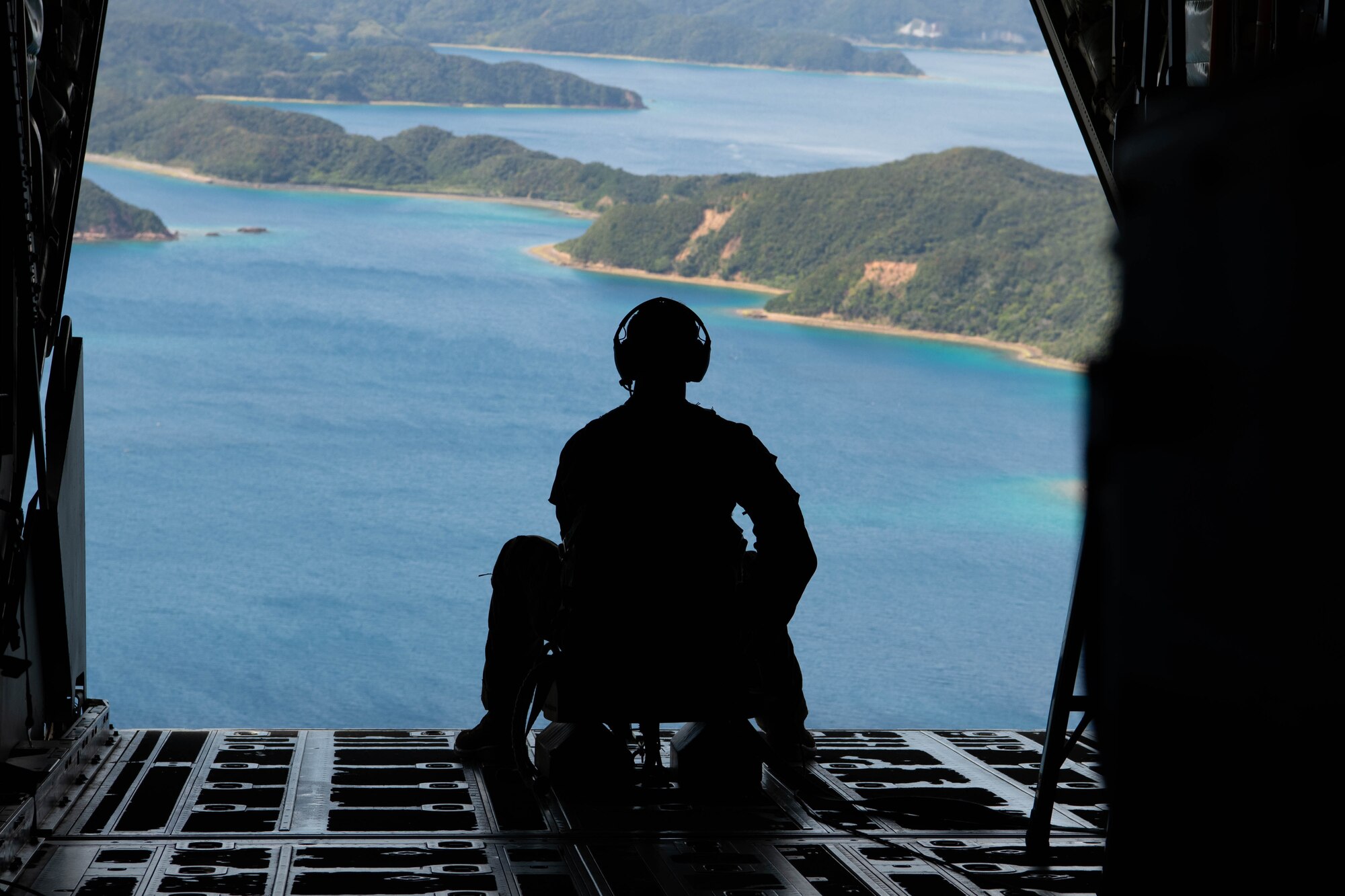 An Airman looks out the back of an aircraft during flight.