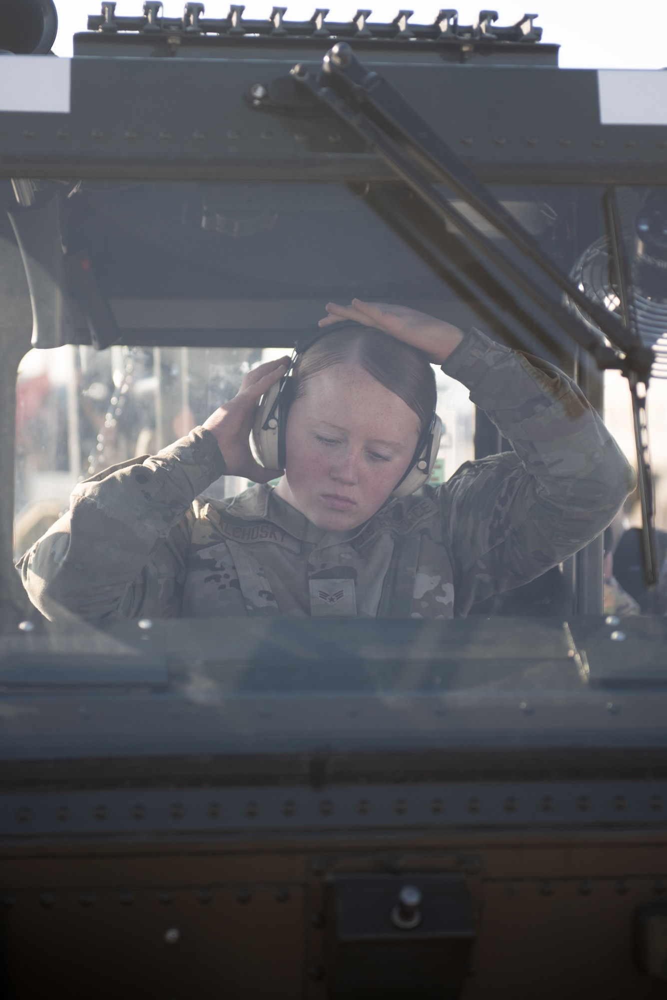 Airman secures hearing protection inside a military vehicle