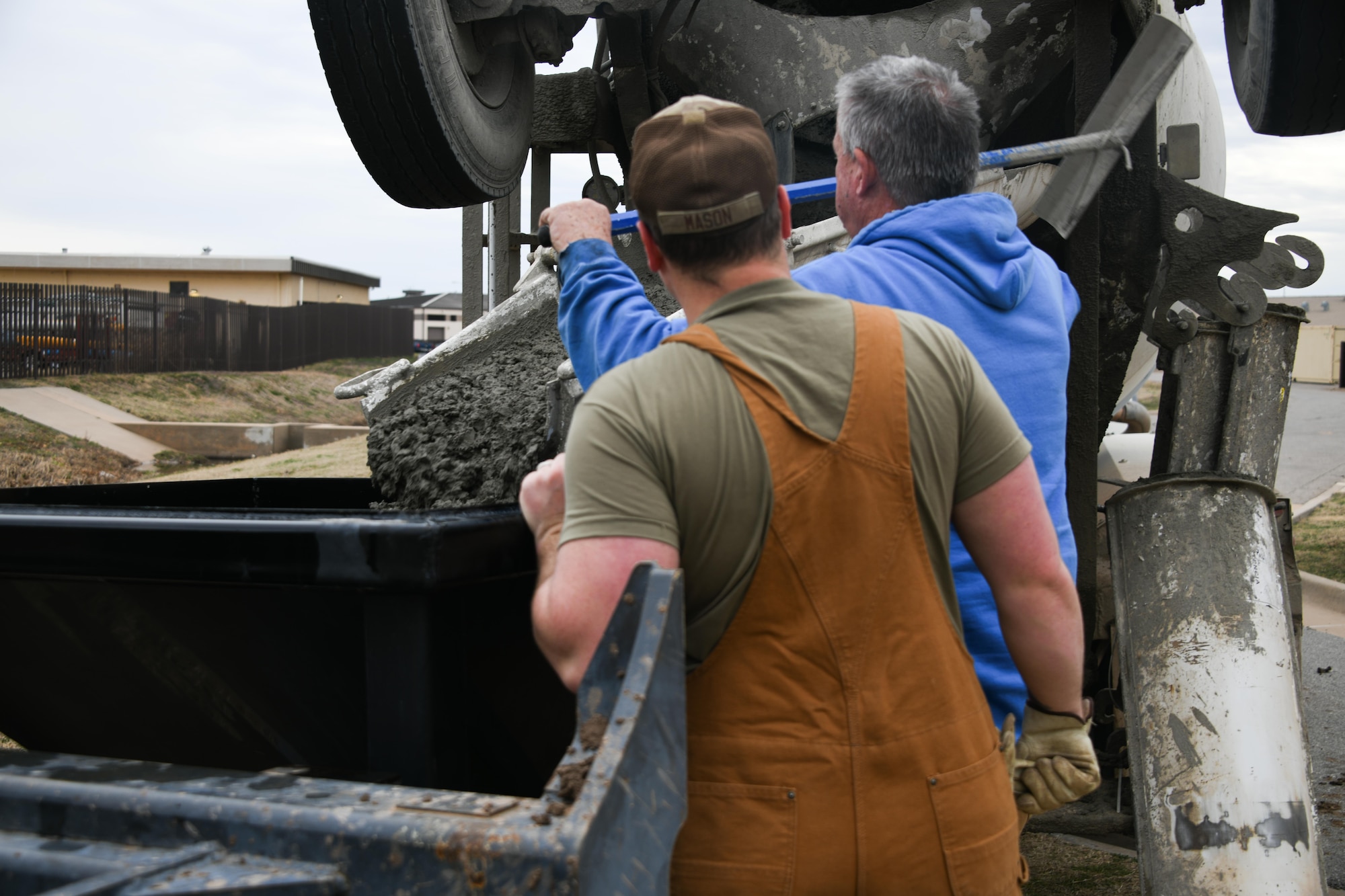 U.S. Air Force Senior Airman John Mason, 97th Civil Engineer Squadron (CES) pavement and equipment journeyman, and James Hukill, 97th CES equipment operator, load cement into a front end loader at Altus Air Force Base, Oklahoma, Feb. 22, 2023. Cement pouring is one of the many jobs Mason does as a “dirt boy.” (U.S. Air Force photo by Airman 1st Class Miyah Gray)
