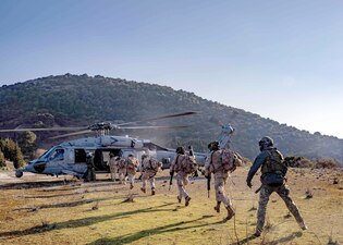 Spanish marines board a U.S. Navy MH-60S Sea Hawk helicopter during interoperability training in Albania.
