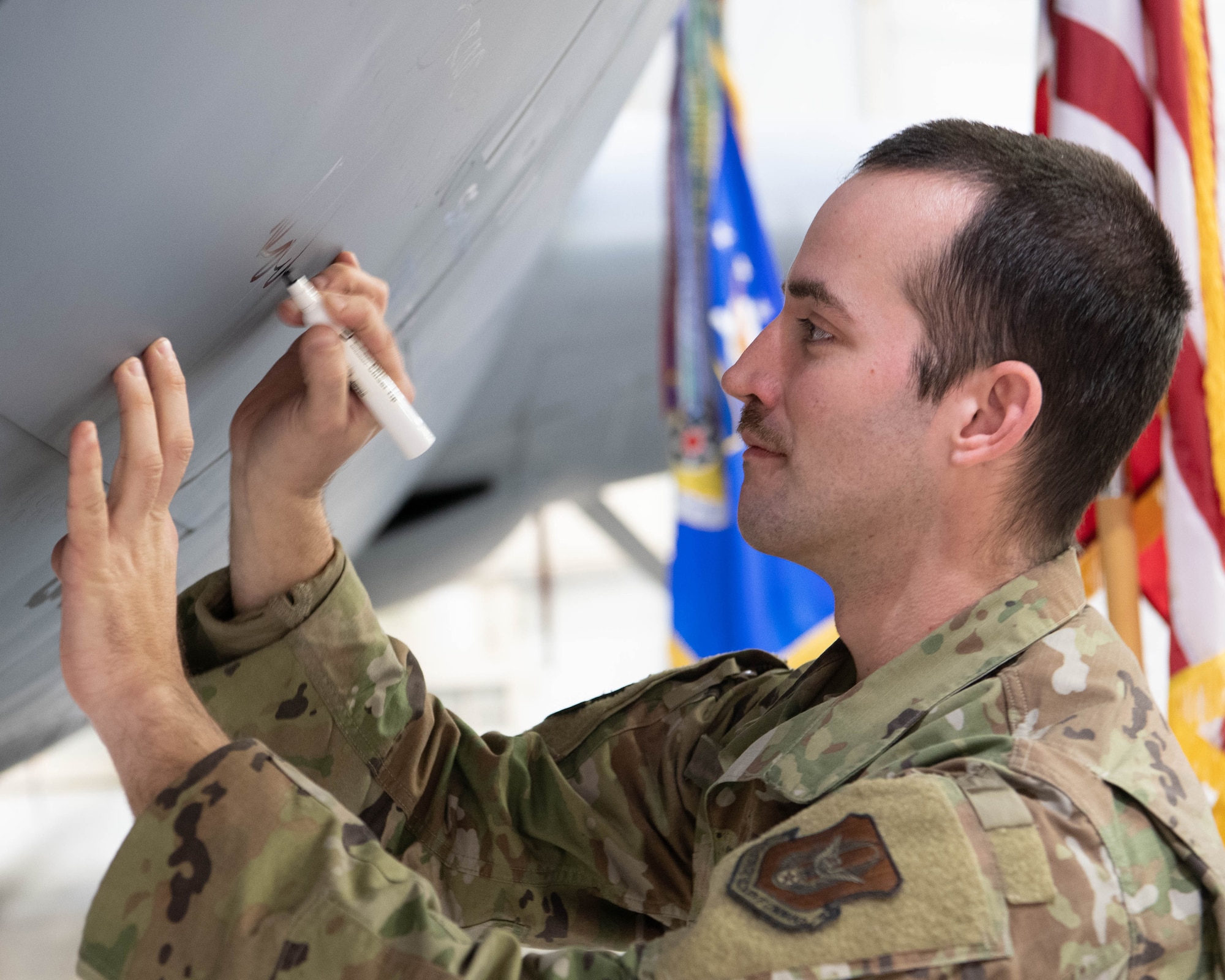 Tech. Sgt. David Adams, 434th Aircraft Maintenance Squadron crew chief signs his name on the side of aircraft 62-3530 during a retirement ceremony for the KC-135.  Adams spent the last five years assigned as the crew chief to the retiring Stratotanker.  (Photo by Douglas Hays)