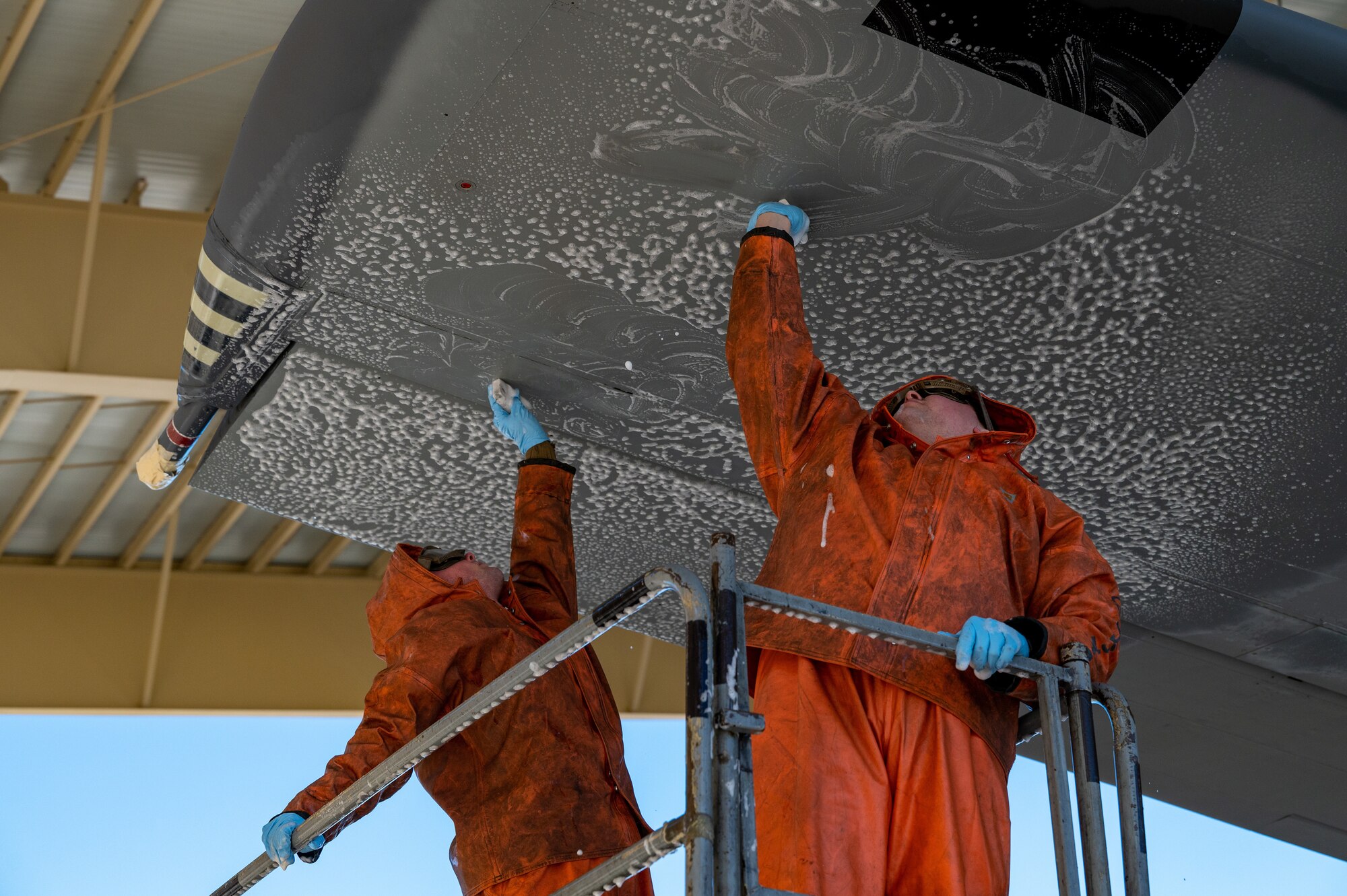 photo of a service member donning personal protective equipment washing a large military aircraft