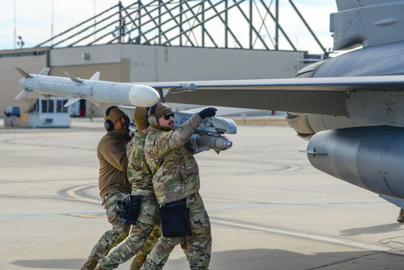 A photo of Airmen with the 177th Aircraft Maintenance Squadron installing an AIM-9 Sidewinder air-to-air training missile onto an F-16C+ Fighting Falcon during Integrated Combat Turnaround training.
