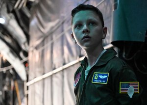 A man and little boy in green flightsuits sit at a table.
