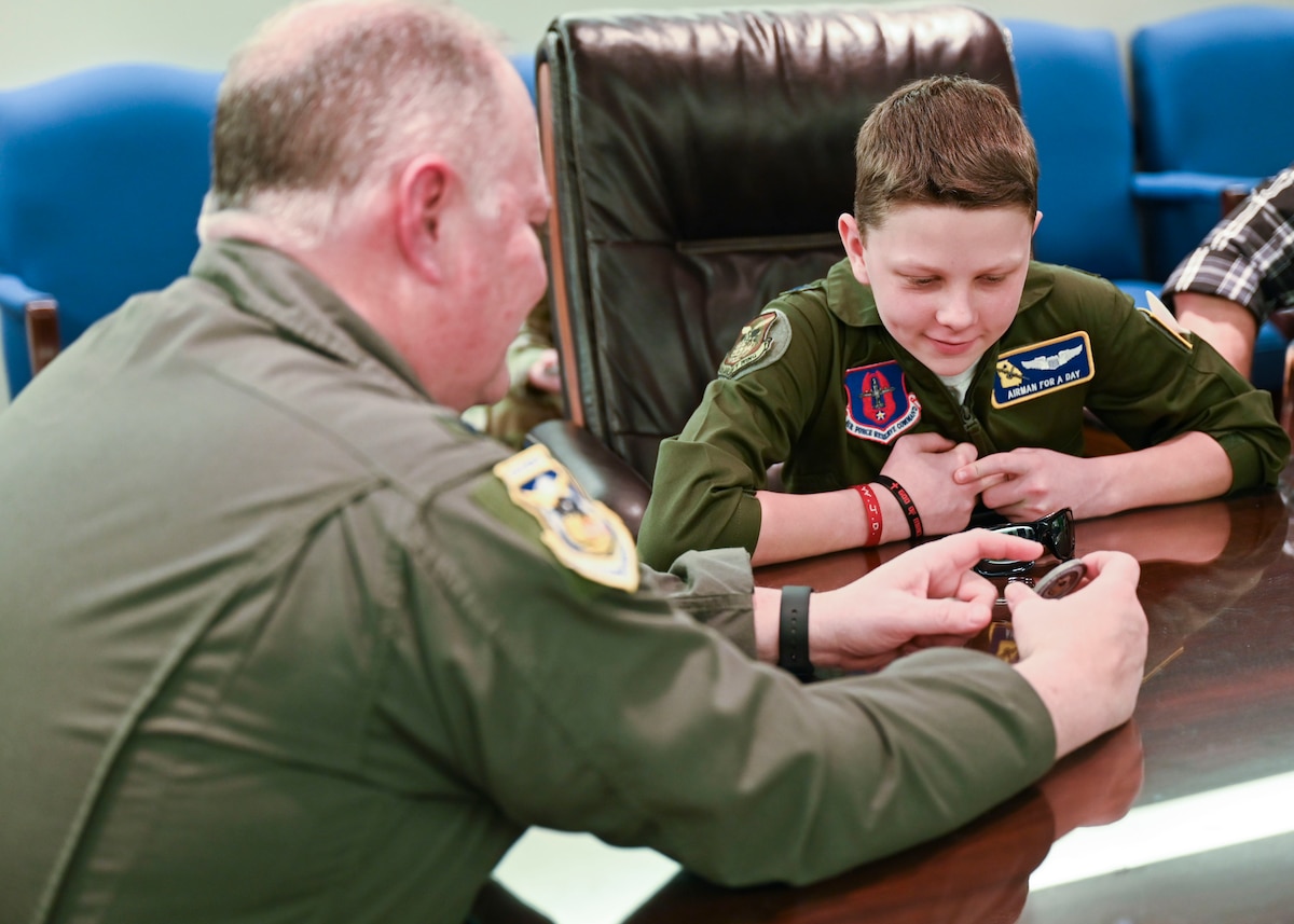 A man and little boy in green flightsuits sit at a table.