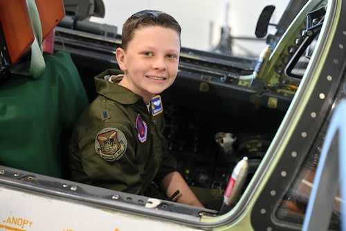 Boy looks at the camera while sitting in the cockpit of an ER-2.
