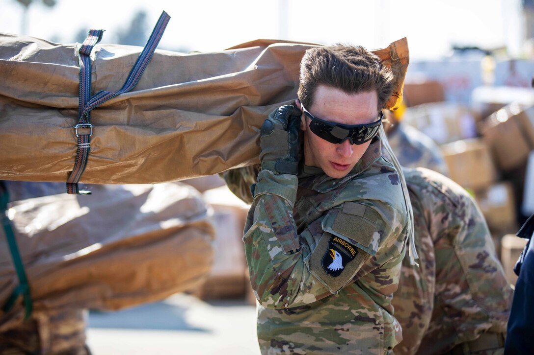 A soldier carries relief supplies that will be loaded on a helicopter.