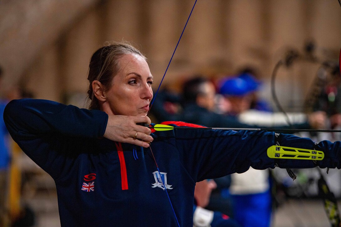 An archer squints as she aims at a target.