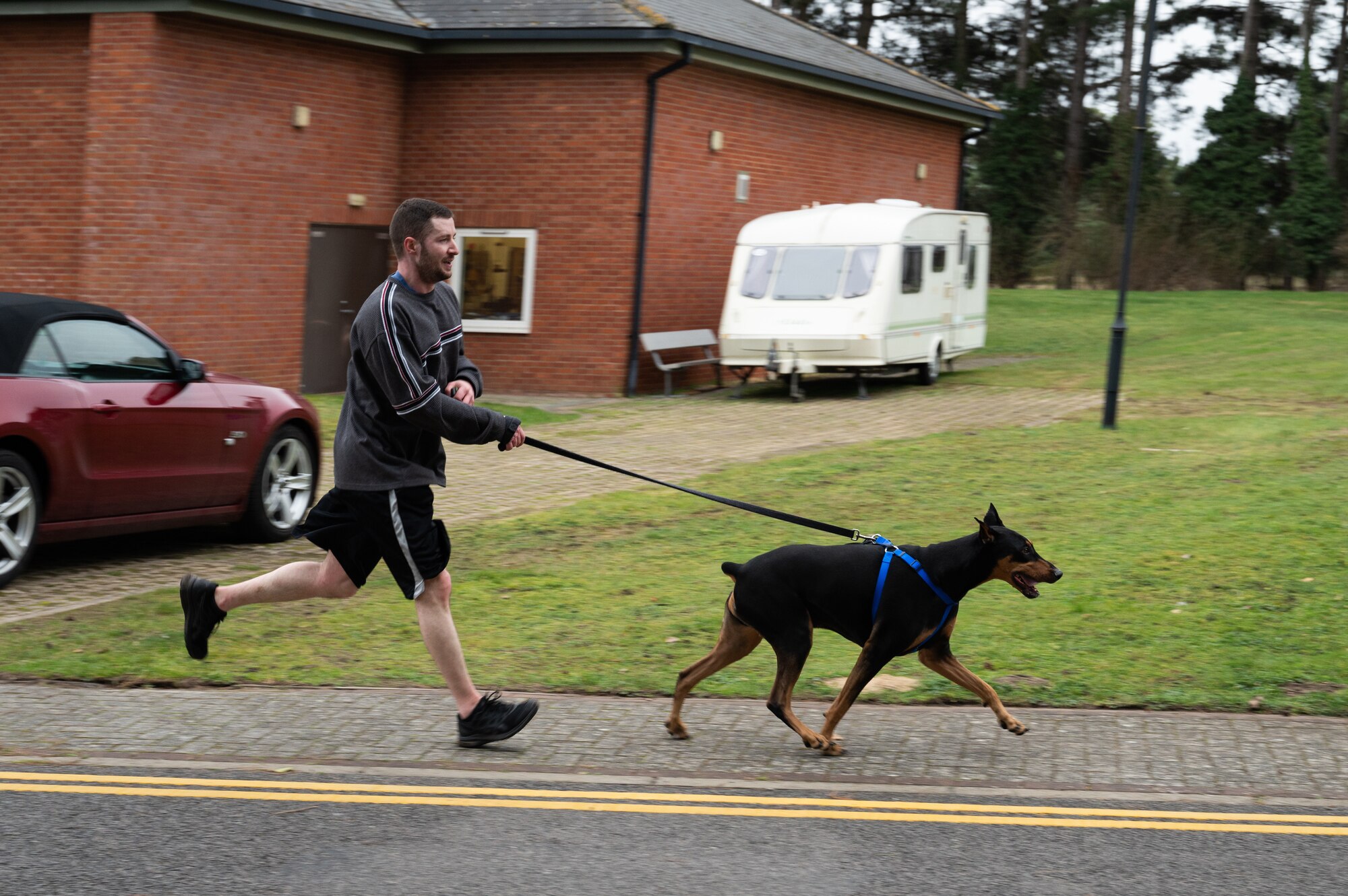 U.S. Air Force Tech. Sgt. Joseph Zinzo, 100th Operations Group unit training manager, sprints towards the finish line with his dog Hades during the Black History Month 5K run and walk, Feb. 23, 2023, at Royal Air Force Mildenhall, England.
