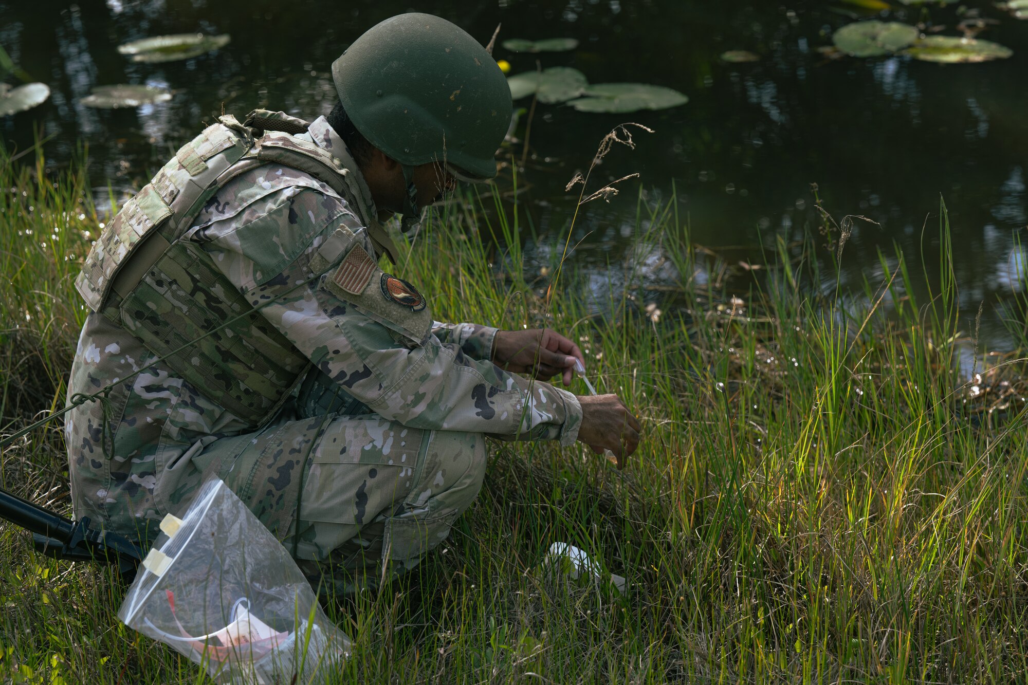 U.S. Air Force Staff Sgt. Micha Hough, an Airman assigned to the 1st Special Operations Civil Engineer Squadron, collects water samples at a nearby stream during an exercise.