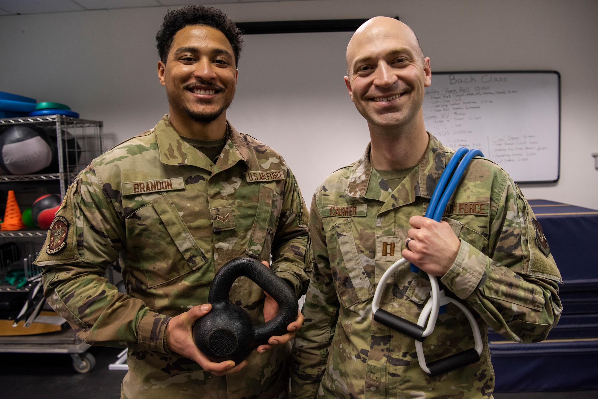 Airmen stand together holding exercise equipment