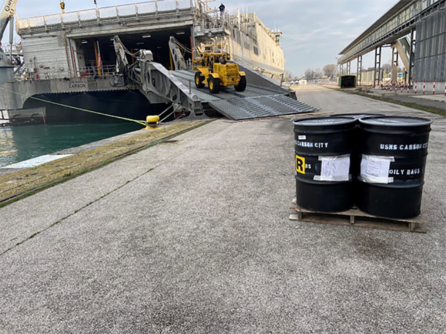 A forklift brings barrels off of a ship.