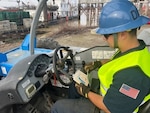 Seaman John Demeraski, a Coast Guard Cutter Kickapoo crewmember reviews a load chart before hoisting buoys with a Genie 6,000 lb. GTH644 telehandler while wearing personal protective equipment. (Photo by Anthony Sciullo, CTR, Support Equipment Program.)