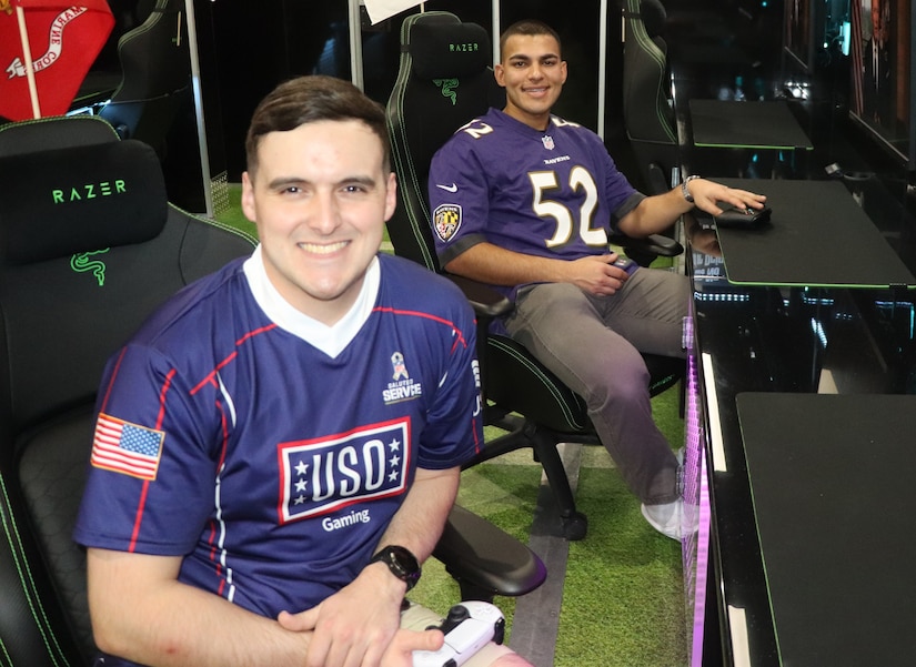 Two men sitting in computer chairs poses for a photo.