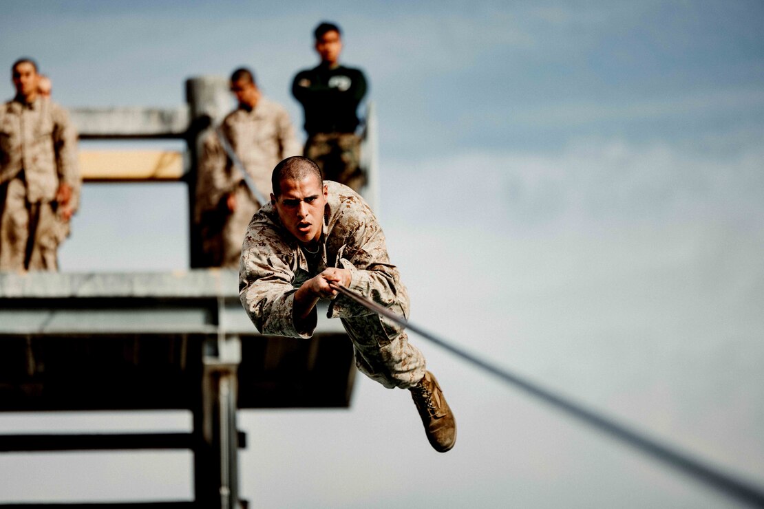 A U.S. Marine Corps recruit with Kilo Company, 3rd Recruit Training Battalion, pulls himself across a rope obstacle during a confidence course event at Marine Corps Recruit Depot San Diego, Feb. 21, 2023.