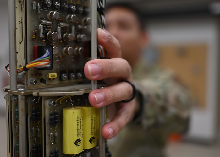 U.S. Air Force Staff Sgt. Christian Bufford, 312th Training Squadron Special Instruments Training instructor, grabs a decommissioned long period seismometer at Goodfellow Air Force Base, Texas, Feb. 21, 2023. The seismometer is a training tool that allows students to identify parts, and provides them a visual aid for how the equipment functions. (U.S. Air Force photo by Staff Sgt. Abbey Rieves)