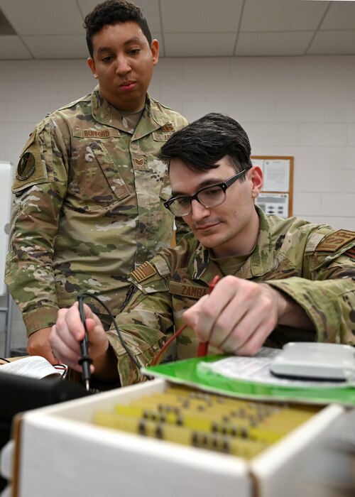 U.S. Air Force Staff Sgt. Christian Bufford, 312th Training Squadron Special Instruments Training instructor, oversees Senior Airman Harrison Zamba, 312th TRS SPINSTRA student, during an electric troubleshooting assignment, at Goodfellow Air Force Base, Texas, Feb. 21, 2023. Zamba used a multimeter to test the voltage across an electrical component to learn about voltages and frequencies. (U.S. Air Force photo by Staff Sgt. Abbey Rieves)