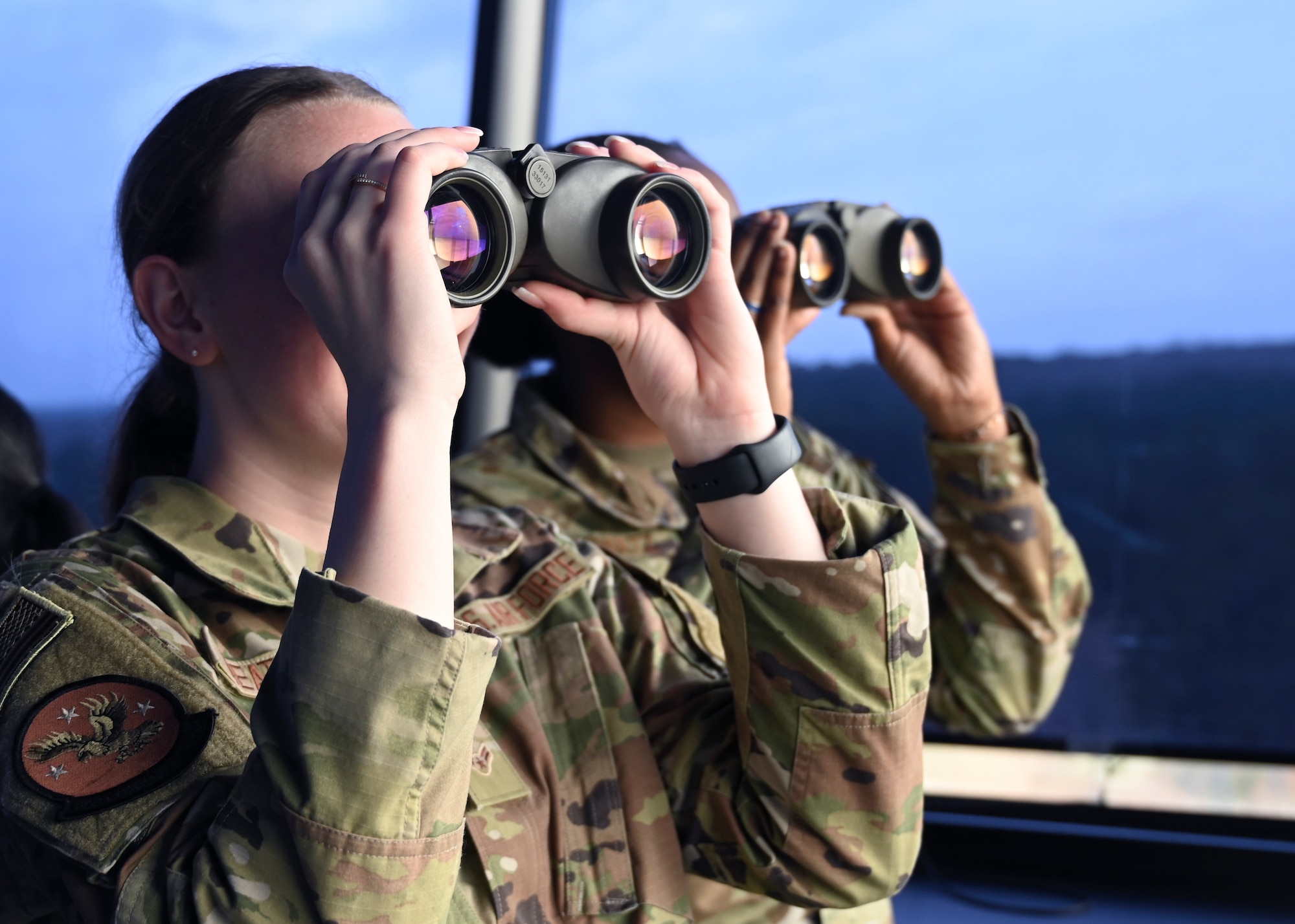 U.S. Air Force Airman 1st Class Erika Weatherly, left, 62d Comptroller Squadron budget analyst and Senior Airman Erica Shultz, 62d Medical Squadron bioenvironmental engineer journeyman, look through binoculars in the air traffic control tower at Columbus Air Force Base, Miss., Feb. 15, 2023. Team McChord Airmen toured Columbus AFB and gained first-hand experience of their mission: Produce Pilots, Advance Airmen, Feed the Fight. (U.S. Air Force photo by Senior Airman Callie Norton)