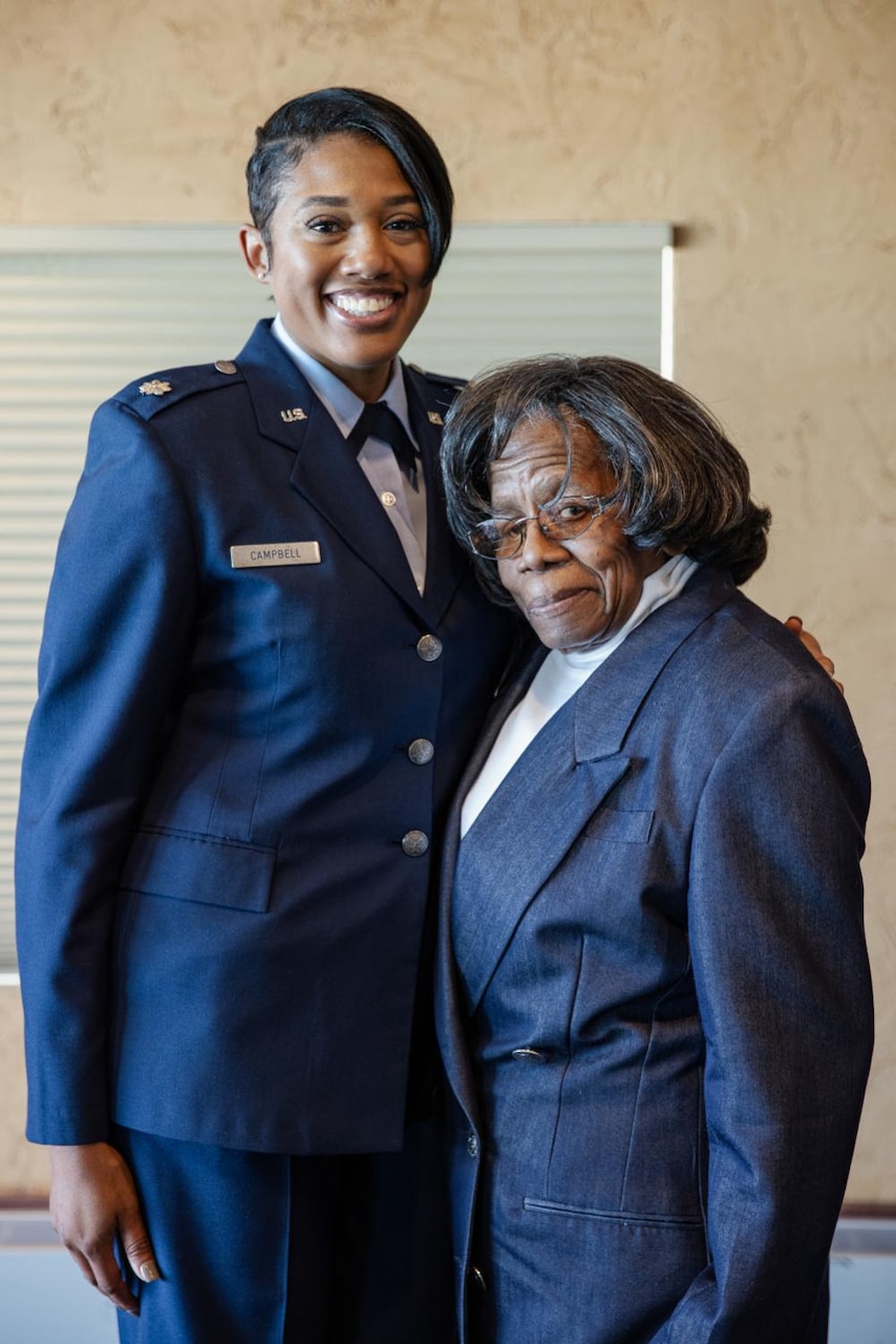 A female uniformed service member stands beside a woman in civilian clothes.