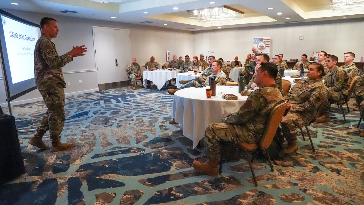 A speaker gives a brief t a room full of Airmen.