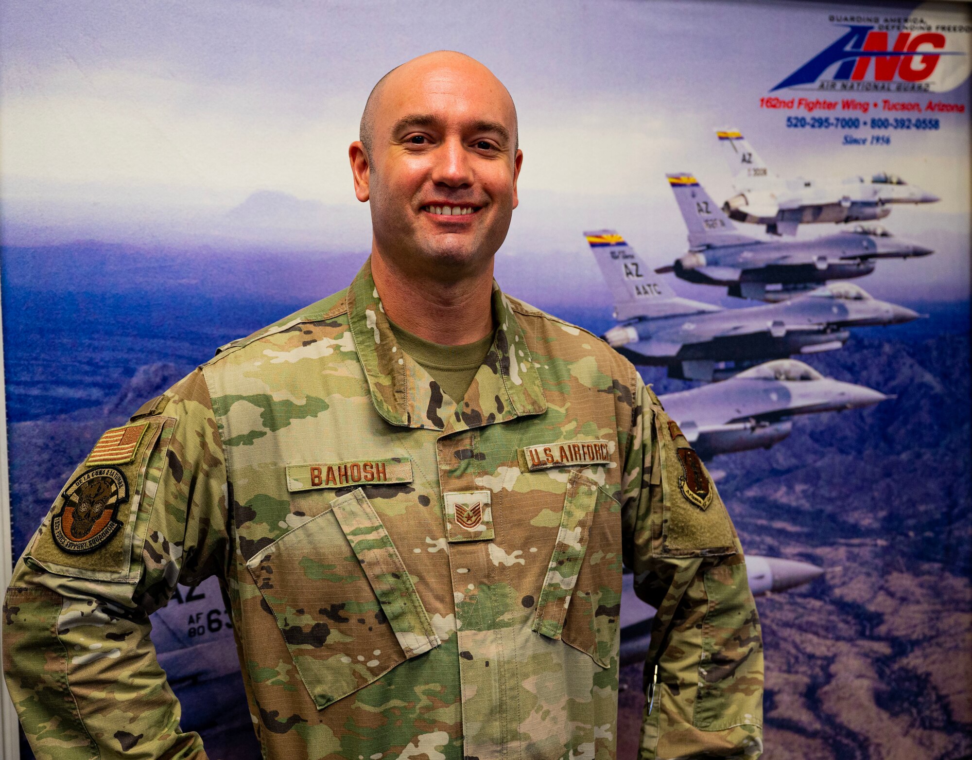 Technical Sgt. Matt Bahosh, an Air National Guard recruiter for the 162nd Wing in Tucson, Arizona, poses for a portrait in front of a recruiting poster in the Arizona Air National Guard recruiting office, Tucson, Ariz. (U.S. Air National Guard photo by SSgt Van C. Whatcott)