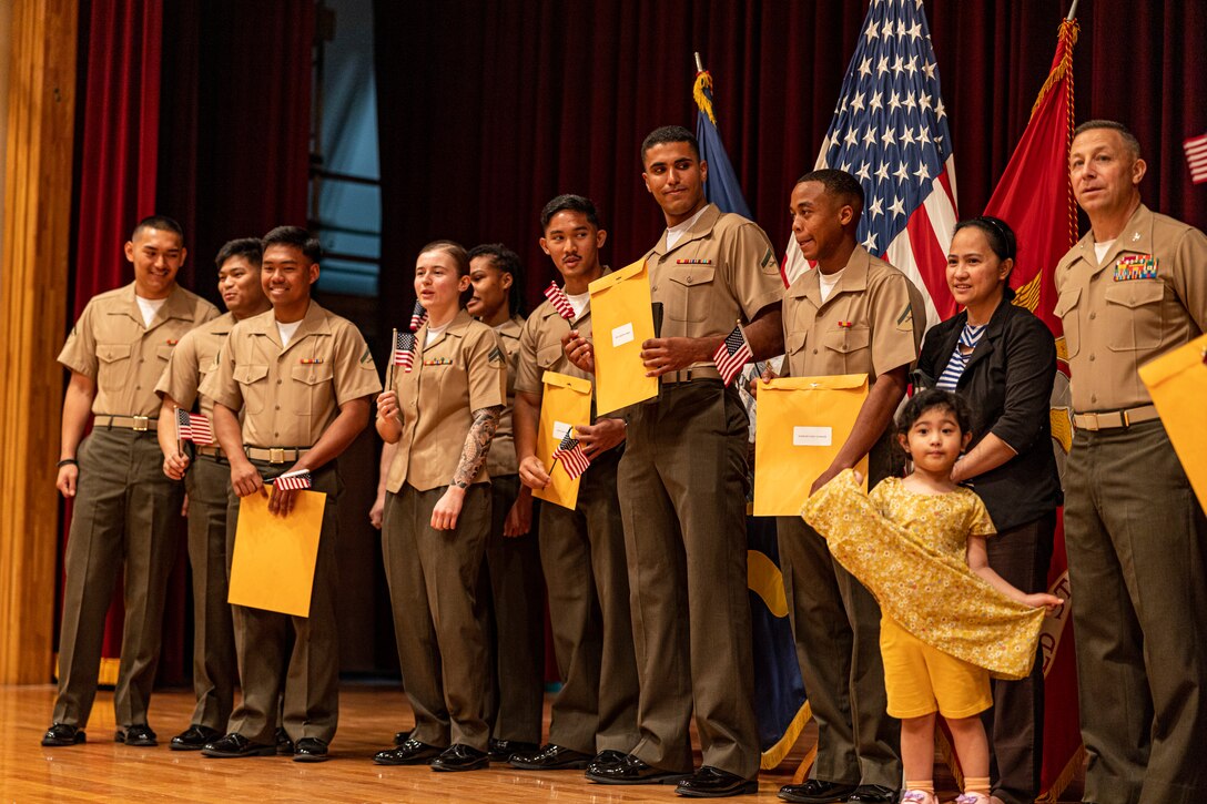 U.S. service members and Status of Forces Agreement Personnel pose for a group photo during a naturalization ceremony hosted at the Community Center on Camp Foster, Okinawa, Japan, Feb. 23, 2023. During the ceremony, a total of 14 service members and Status of Forces Agreement personnel received their U.S. citizenship and naturalization certificates, commemorated by a recital of the Oath of Allegiance. After fulfilling the requirements to become a citizen, established by Congress in the Immigration and Nationality Act of 1965, U.S. citizenship is officially granted to a foreign citizen through a naturalization ceremony. (U.S. Marine Corps photo by Cpl. Alex Fairchild)