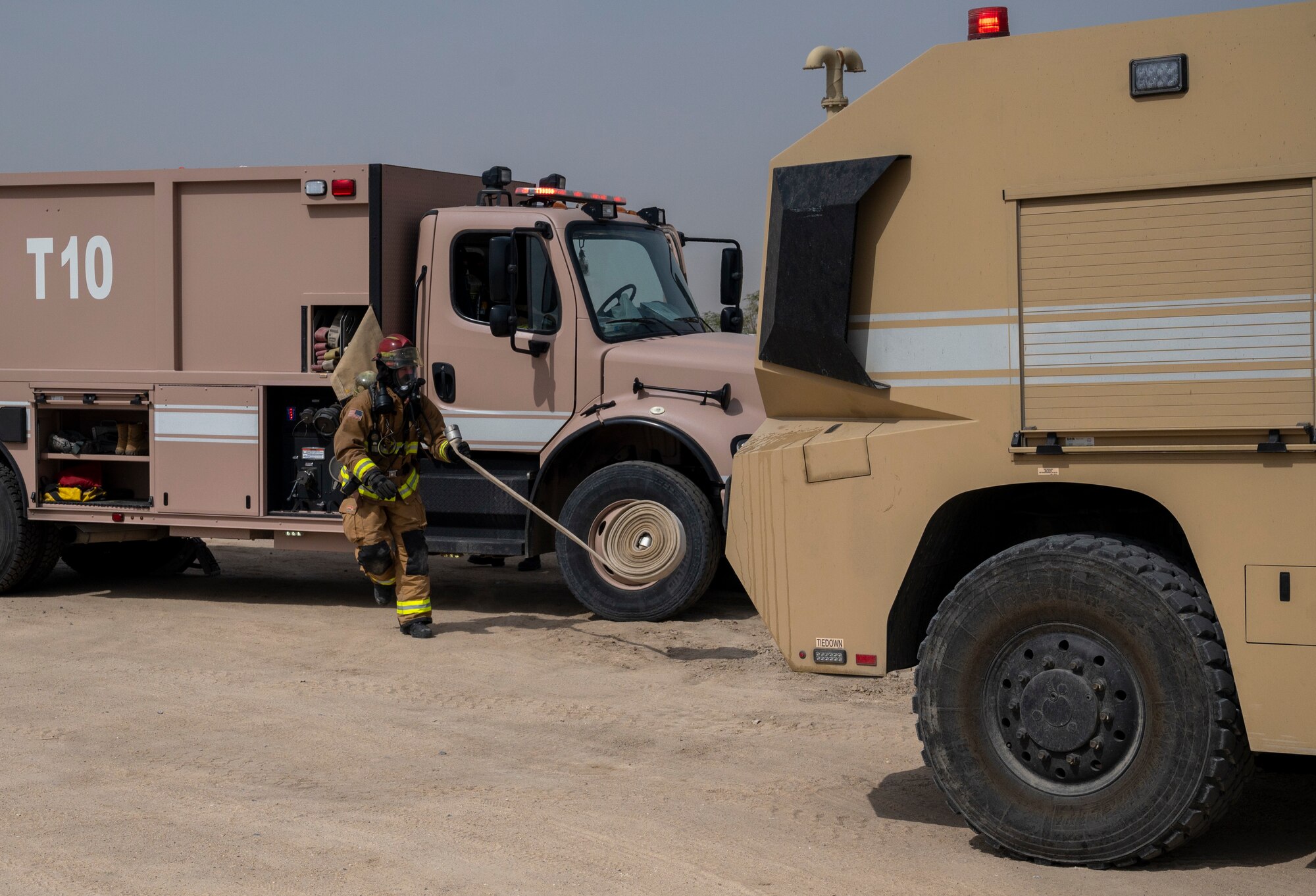 U.S. Air Force Staff Sgt. Trevor McCleary, a 386th Expeditionary Civil Engineer Squadron firefighter, throws a hose to unroll it while running to link it to another fire truck during an Unmanned Aircraft System response exercise at Ali Al Salem Air Base, Kuwait, Feb. 21, 2023.