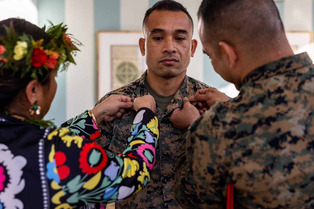 U.S. Marine Corps Staff Sgt. Steve Asher, a utilities officer with 1st Combat Engineer Battalion, 1st Marine Division, center, has his cousin, left, and U.S. Marine Corps Capt. Jack Kun, an aviation supply officer with Marine Helicopter Squadron 1, right, place the rank of warrant officers on his collar during his pinning ceremony to warrant officer on Marine Corps Base Quantico, Virginia, Feb. 1, 2023. The Ambassador of the Federated States of Micronesia to the United States, family and friends attended the promotion ceremony of Asher and Tolenoa who joined the Marine Corps from the Federated States of Micronesia. (U.S. Marine Corps photo by Lance Cpl. Joaquin Dela Torre)