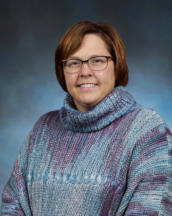 Professional portrait of female with blue background.