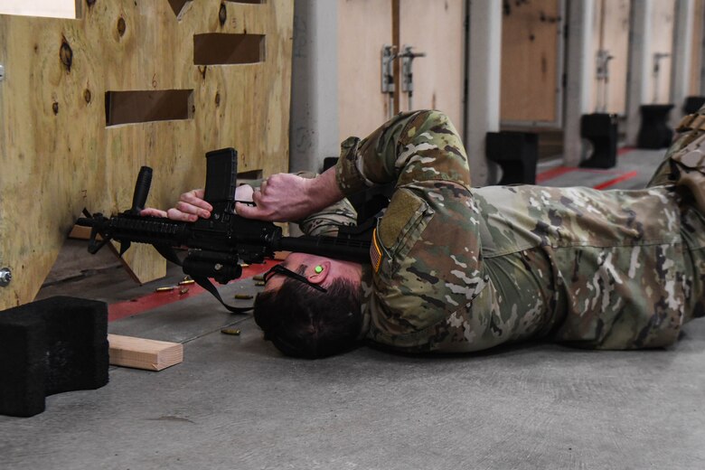 Man lies on floor and aims weapon at target
