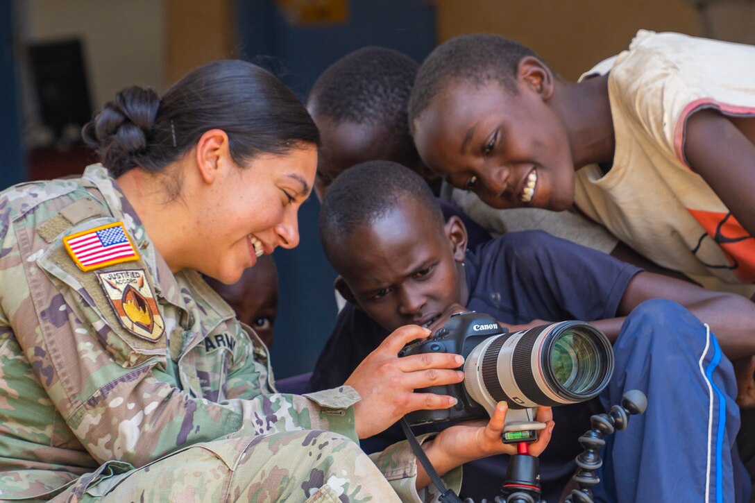 A soldier shows children images on a camera.