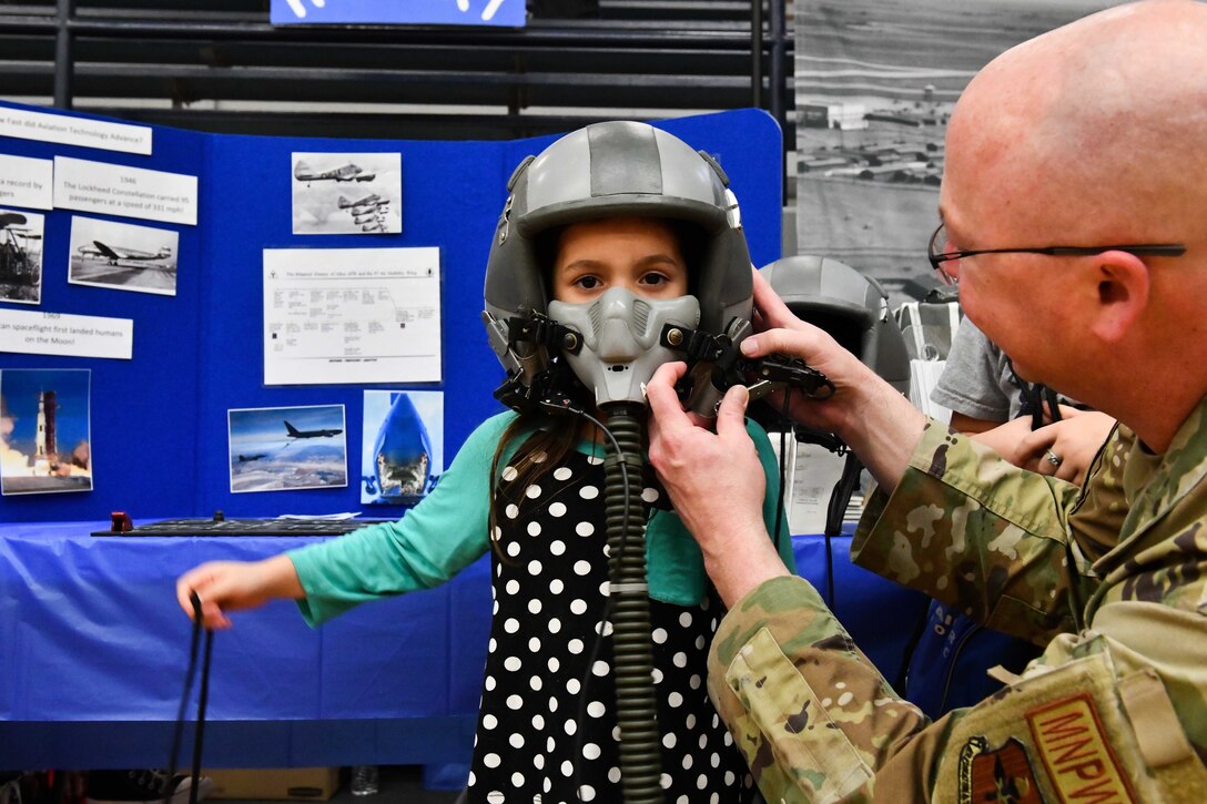 U.S. Air Force Master Sgt. Matthew Sims, 97th Force Support Squadron manpower and organization superintendent, places a flight helmet on a child during an aviation fair at Altus Junior High School, Oklahoma, Feb. 25, 2023. This event gave Airmen an opportunity to teach and mentor children from the Altus community about aviation. (U.S. Air Force photo by Airman 1st Class Miyah Gray)