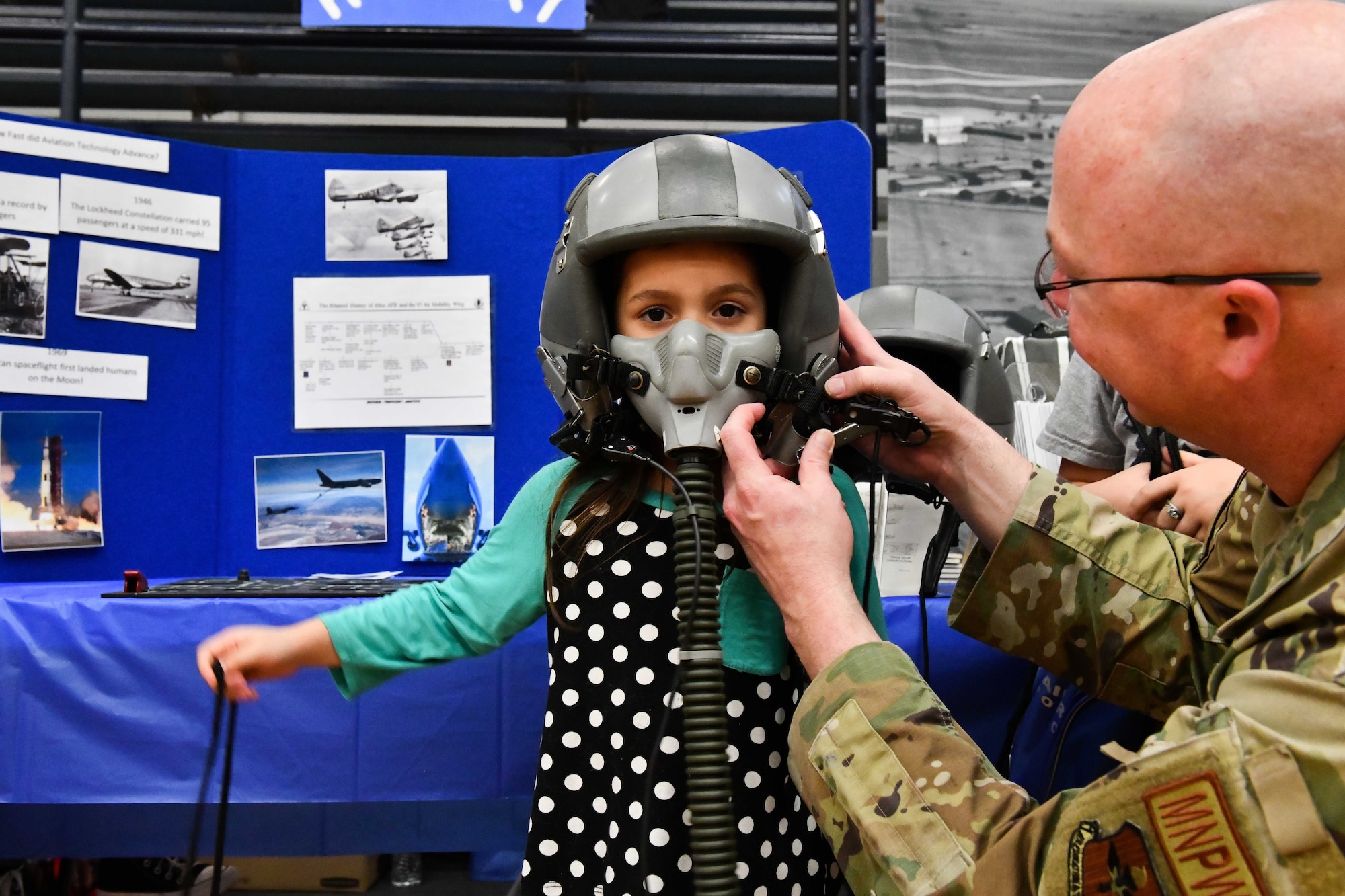 U.S. Air Force Master Sgt. Matthew Sims, 97th Force Support Squadron manpower and organization superintendent, places a flight helmet on a child during an aviation fair at Altus Junior High School, Oklahoma, Feb. 25, 2023. This event gave Airmen an opportunity to teach and mentor children from the Altus community about aviation. (U.S. Air Force photo by Airman 1st Class Miyah Gray)