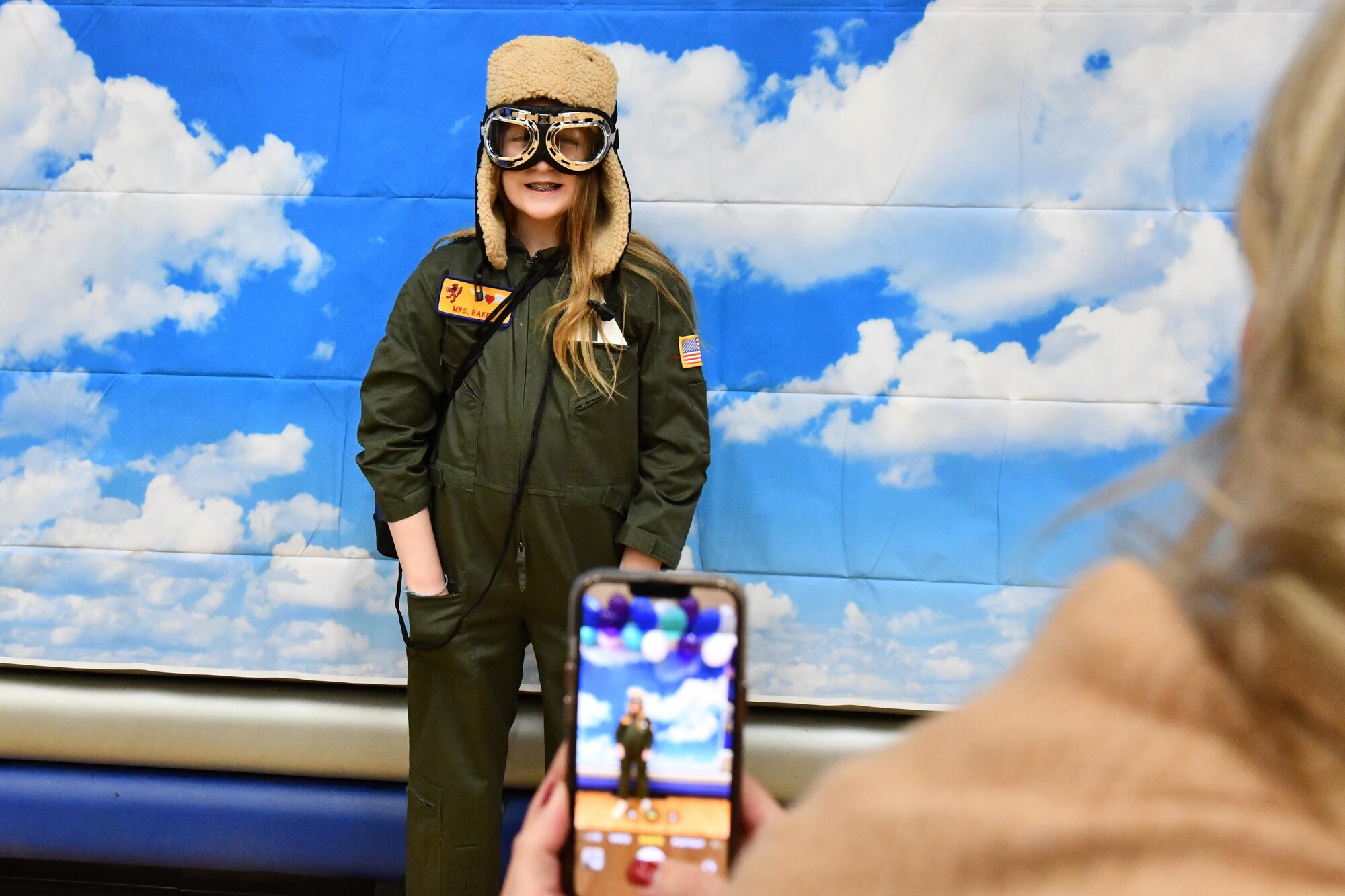 Tara Stewart, spouse of U.S. Air Force Lt. Col. Andy Stewart, 97th Force Support Squadron commander, takes a photo of Samantha Baker, daughter of Col. Blaine Baker, 97th Air Mobility Wing commander, during an aviation fair at Altus Junior High School, Altus, Oklahoma, Feb. 25, 2023. The event featured many immersive activities focused on aviation, science, technology, engineering and math. (U.S. Air Force photo by Airman 1st Class Miyah Gray)