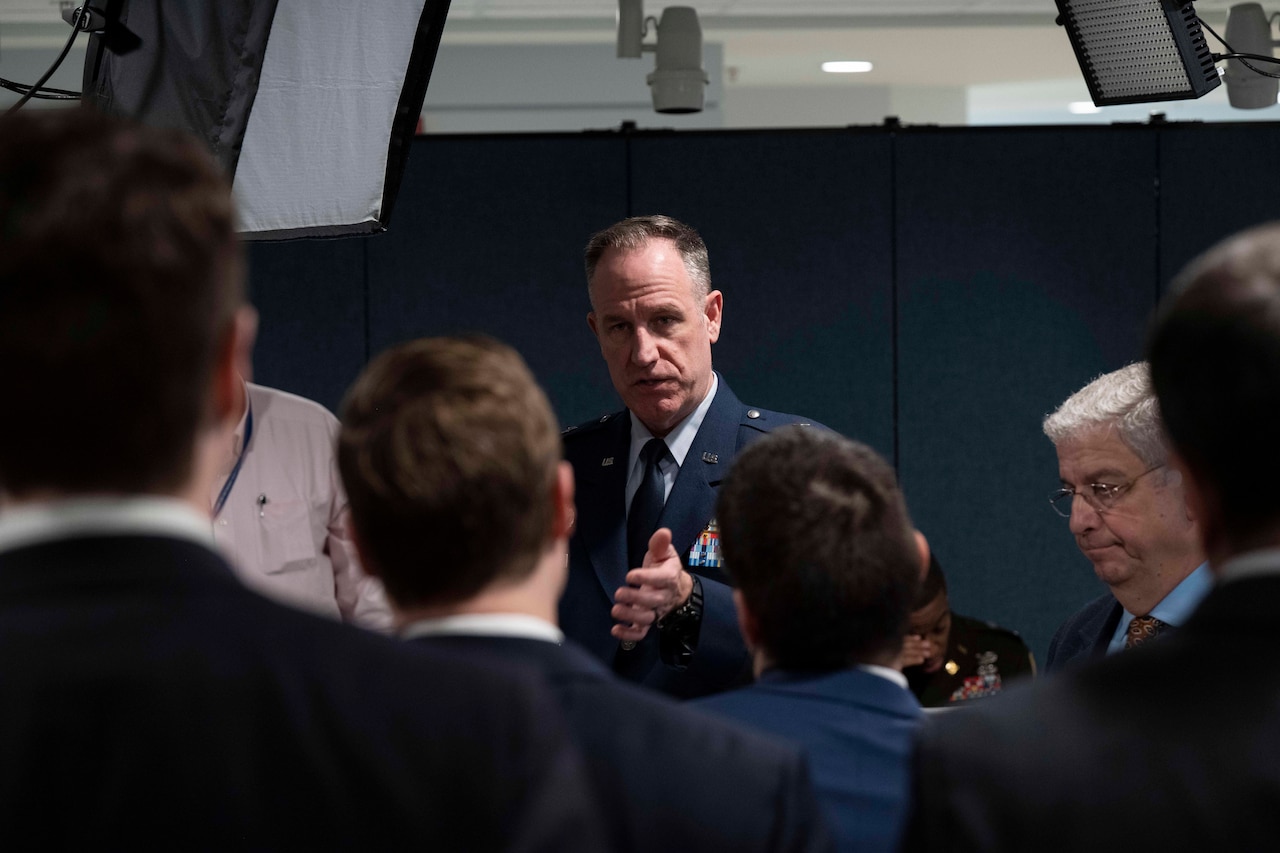 A man in uniform speaks to a group.