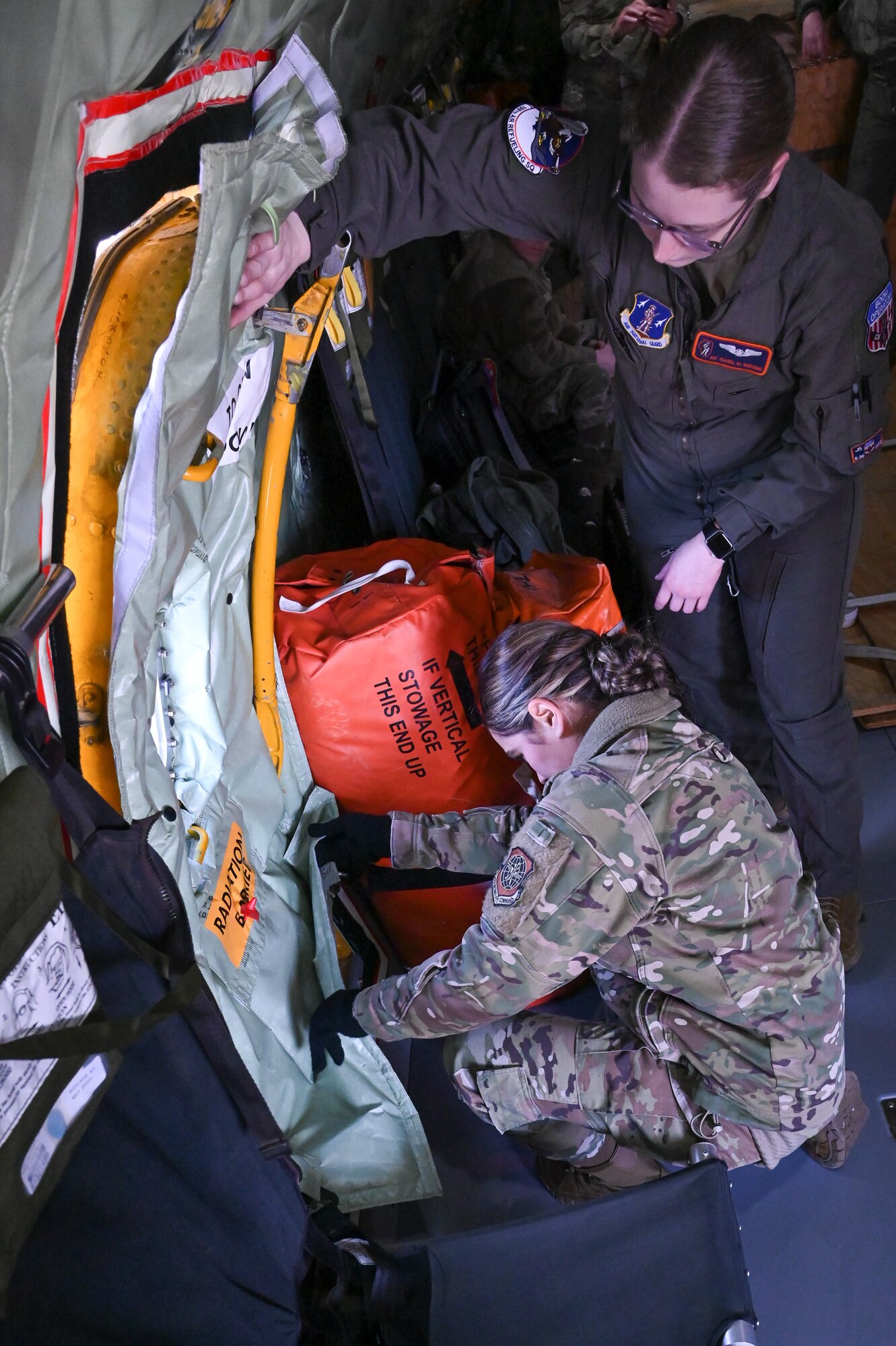 A U.S. Air Force member checks the seal on an KC-135 emergency exit door while a second person talks her through the process.