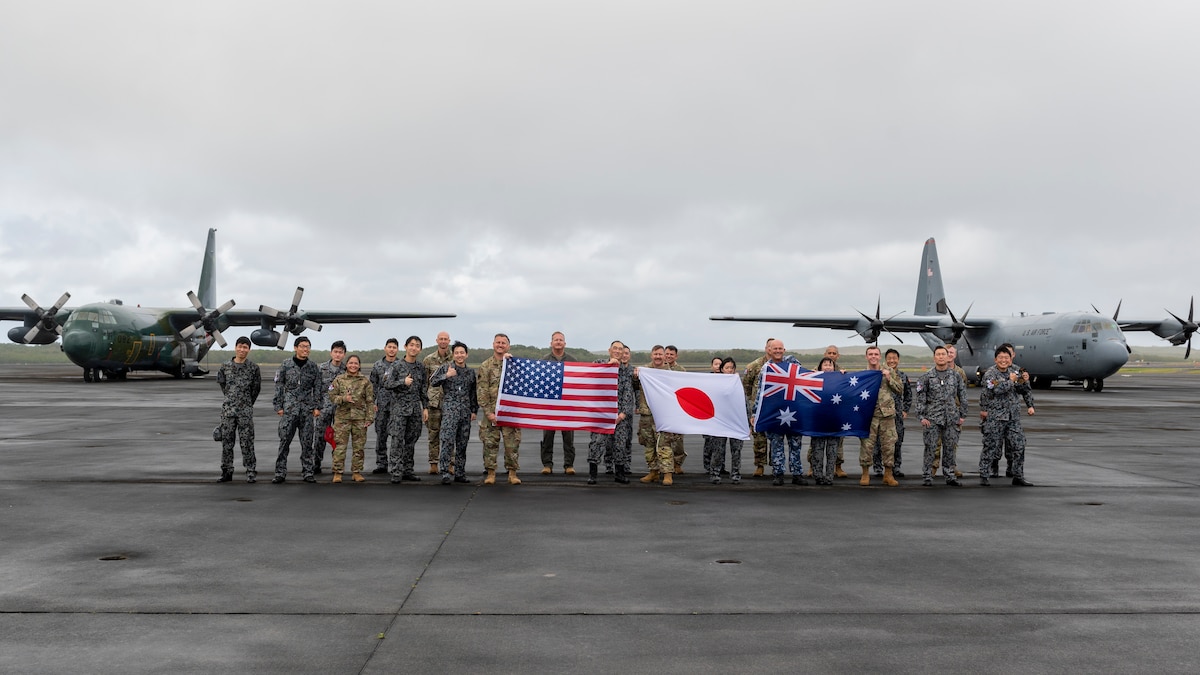 A team of U.S. Air Force, Japan Maritime Self-Defense Force, and Royal Australian Air Force members pose for a photo with a U.S. C-130J Super Hercules from the 36th Airlift Squadron (right), and a JMSDF C-130H Hercules during the Cope North 23 exercise, on the remote island of Iwo Jima, Japan, Feb. 21, 2023.