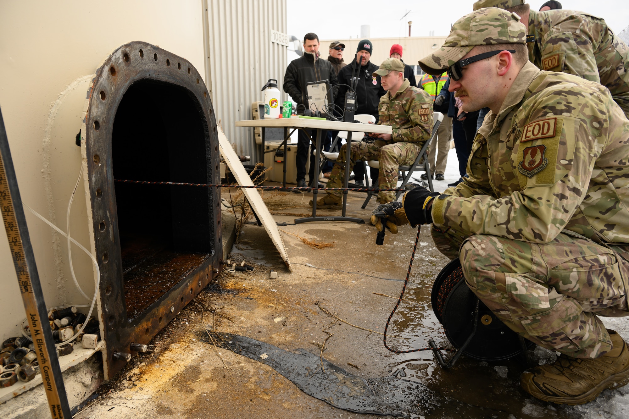 An airman looks into the manhole of a fuel tank