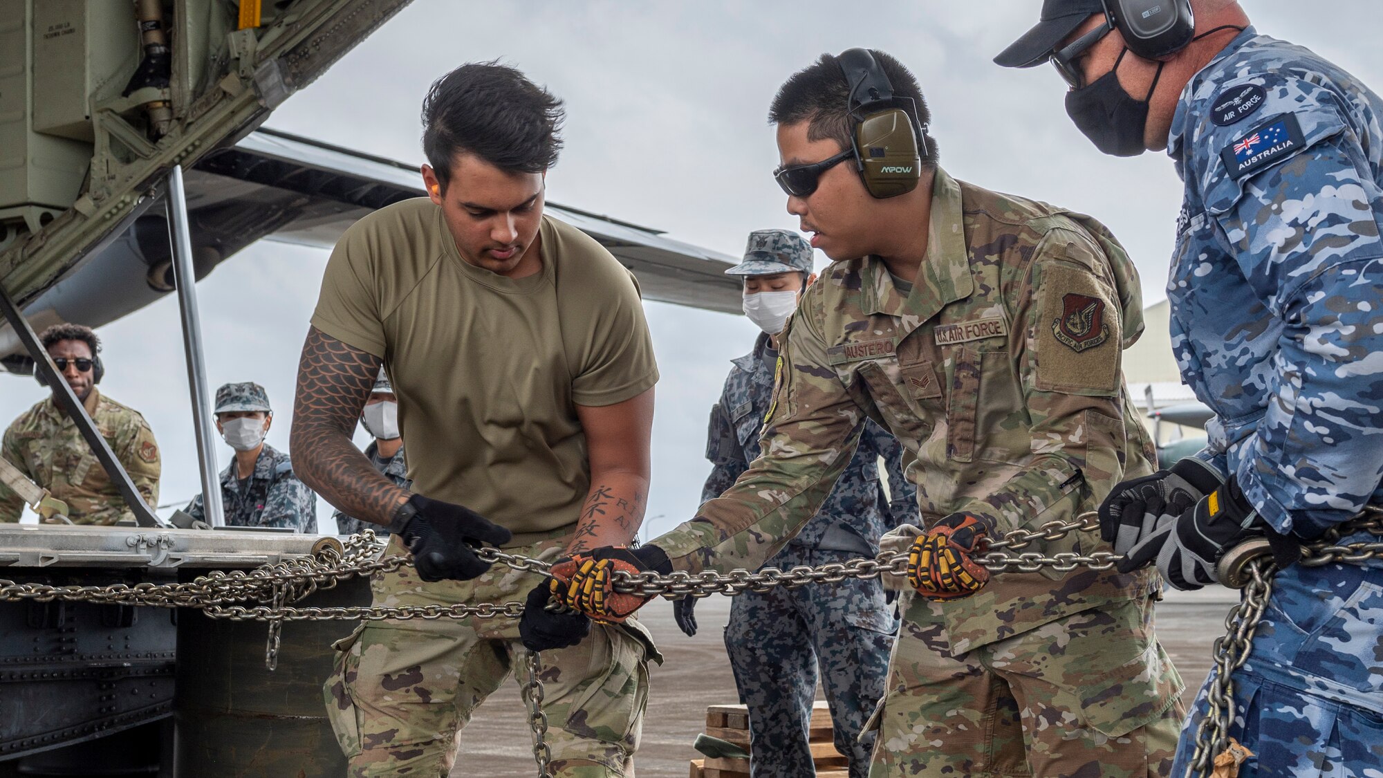 Royal Australian Air Force Corporal Jeremy Anderson, 383rd Squadron air cargo movement specialist (right), works alongside U.S. and Japan Maritime Self-Defense Force members to pull a large cargo pallet from a 36th Airlift Squadron C-130J Super Hercules onto storage barrels using combat offloading during the Cope North 23 exercise, on the remote island of Iwo Jima, Japan, Feb. 21, 2023.