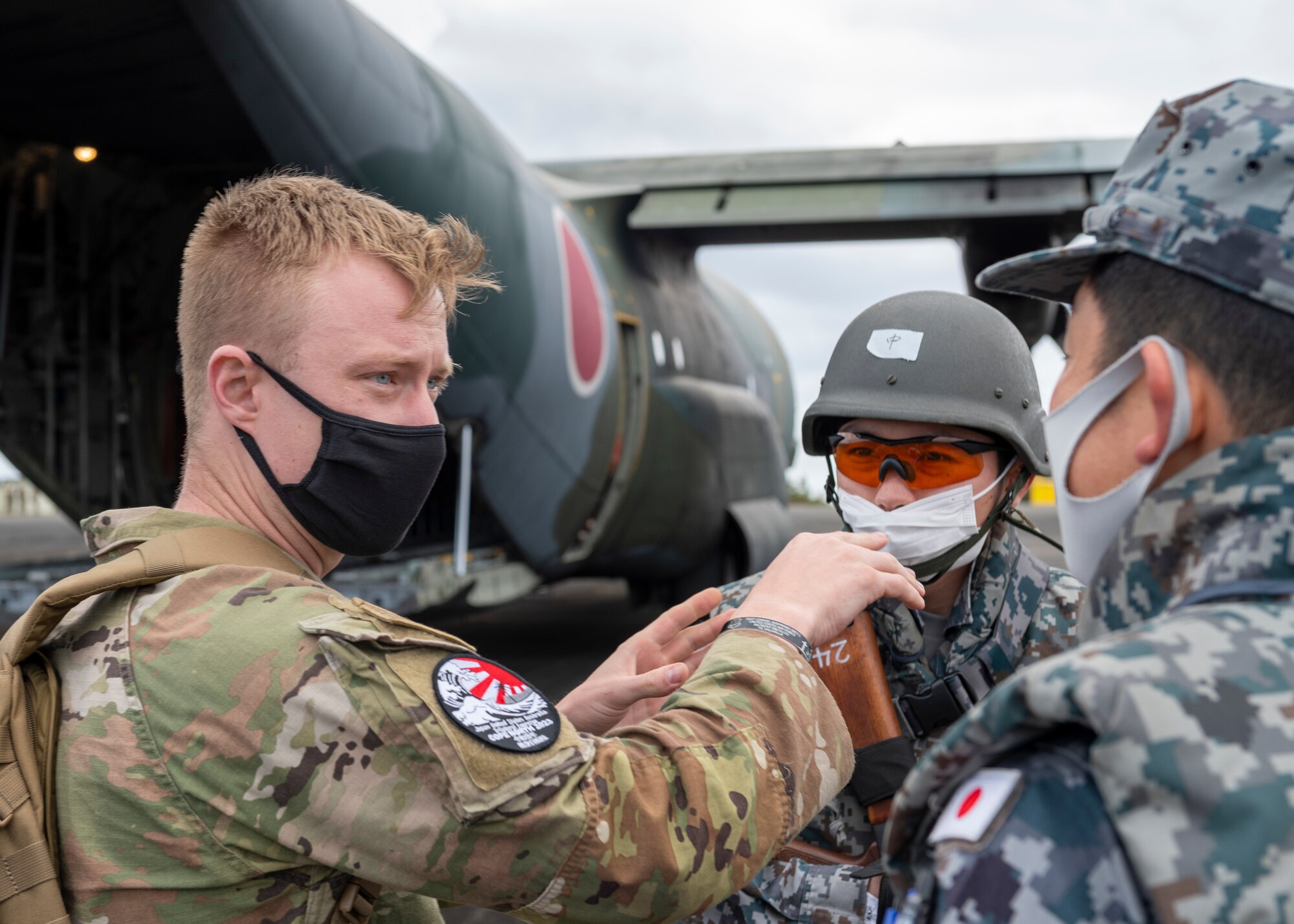 U.S. Air Force Staff Sgt. Joshua Tate, 36th Airlift Wing religious affairs specialist who headed security training for the deployed team at Iwo Jima, discusses aircraft security measures with Japan Maritime Self-Defense Force during practice drills with a JMSDF C-130H Hercules during the Cope North 23 exercise, Feb. 21, 2023.