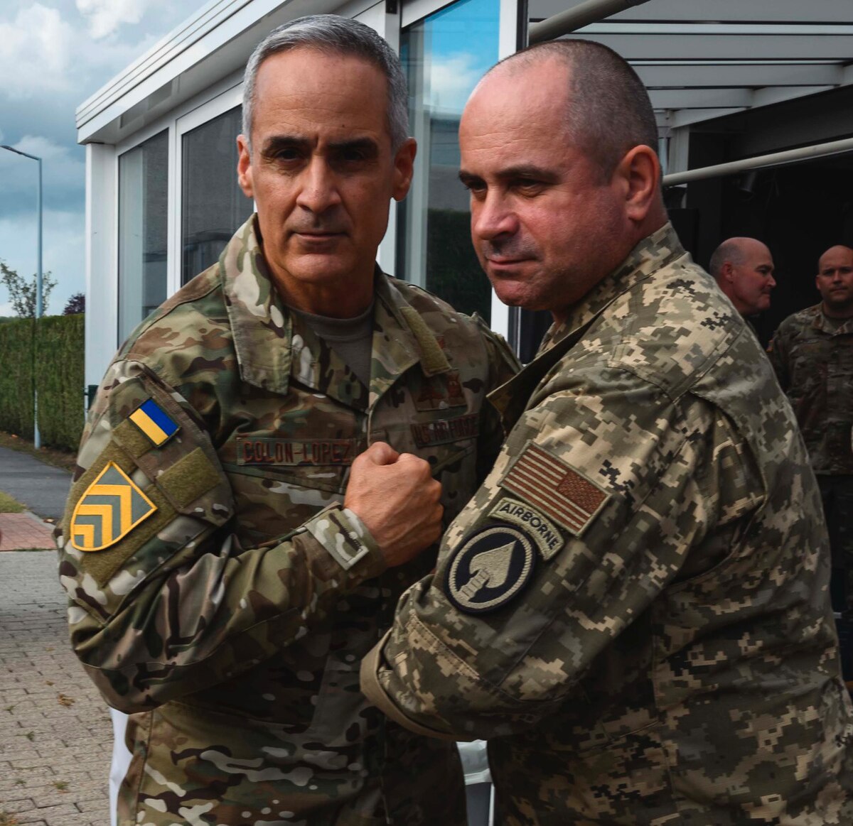 Two uniformed service members display the patches on the sleeve of their uniforms.