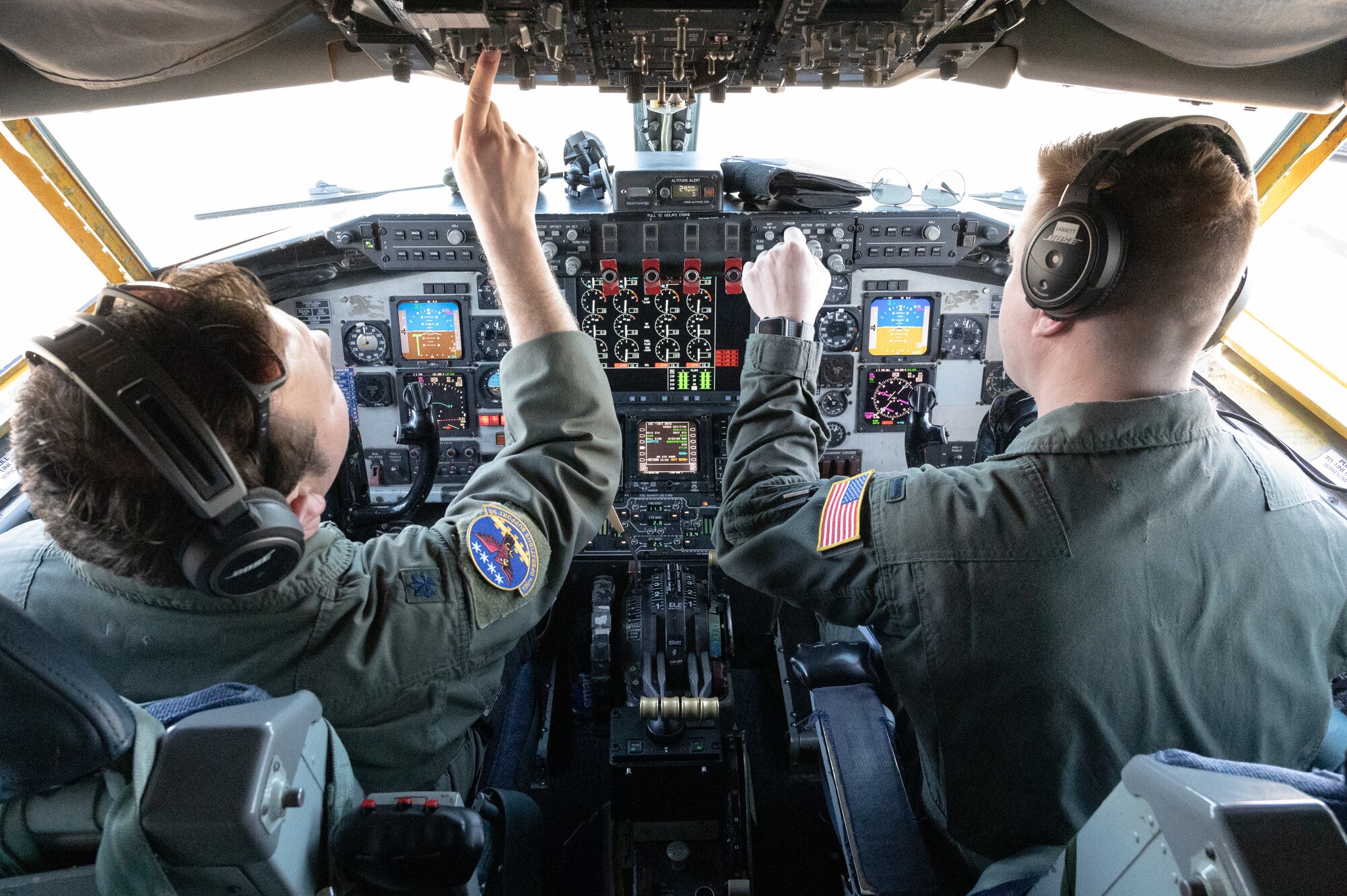 Two U.S. Air Force pilots check their control settings while doing a preflight checklist in the cockpit of a KC-135.