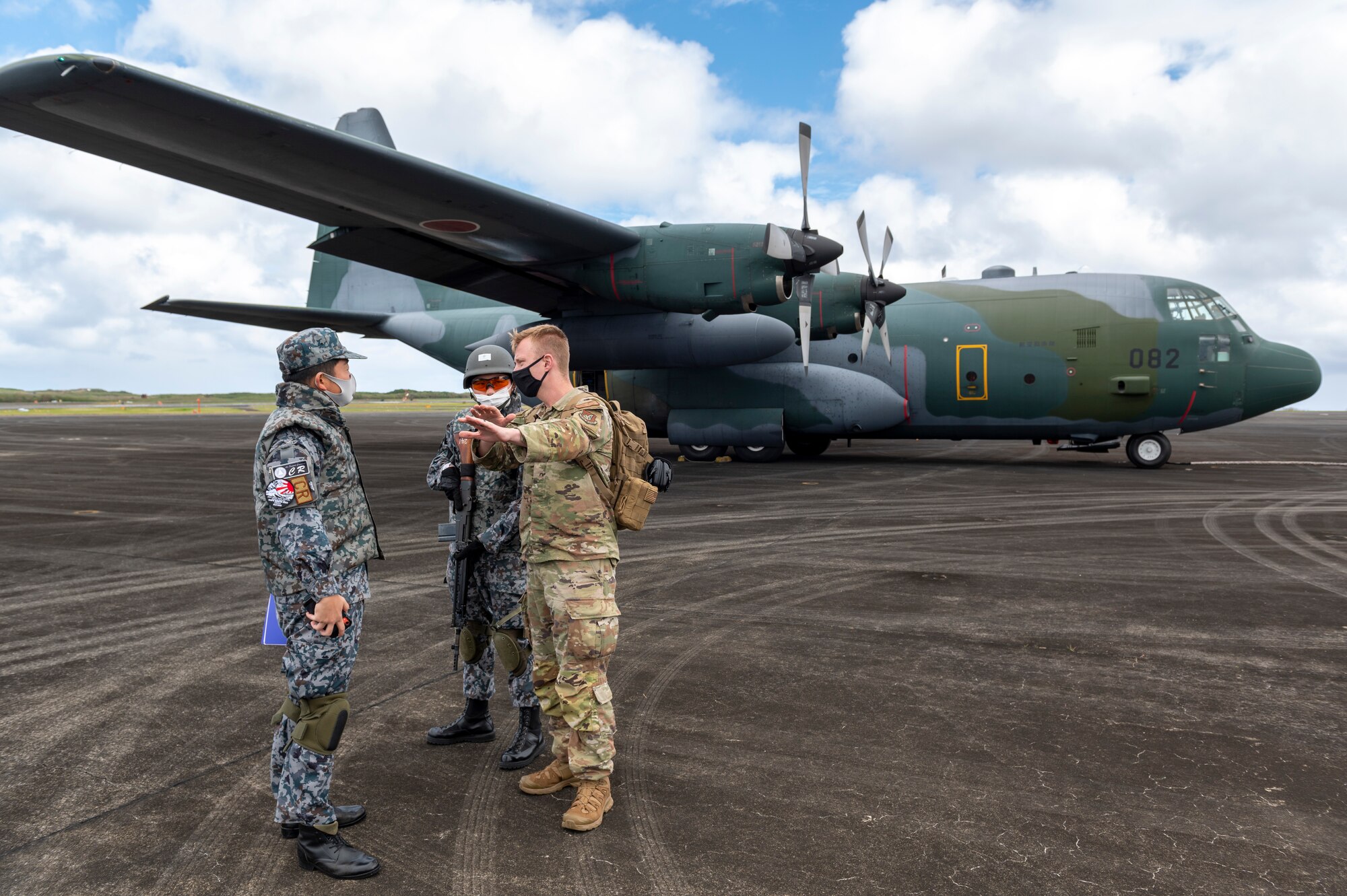 U.S. Air Force Staff Sgt. Joshua Tate, 36th Airlift Wing religious affairs specialist who headed security training for the deployed team at Iwo Jima, discusses aircraft security measures with Japan Maritime Self-Defense Force during practice drills with a JMSDF C-130H Hercules during the Cope North 23 exercise, Feb. 21, 2023.