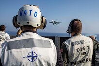 (Oct. 25, 2022) Jens Stoltenberg, Secretary General of NATO, left, observes flight operations on the flight deck of the Nimitz-class aircraft carrier USS George H.W. Bush (CVN 77) for a scheduled visit during the NATO-led vigilance activity Neptune Strike 2022.2 (NEST 22.2), Oct. 25, 2022. NEST 22.2 is the natural evolution of NATO's ability to integrate the high-end maritime warfare capabilities of a carrier strike group to support the defense of the alliance in Europe.