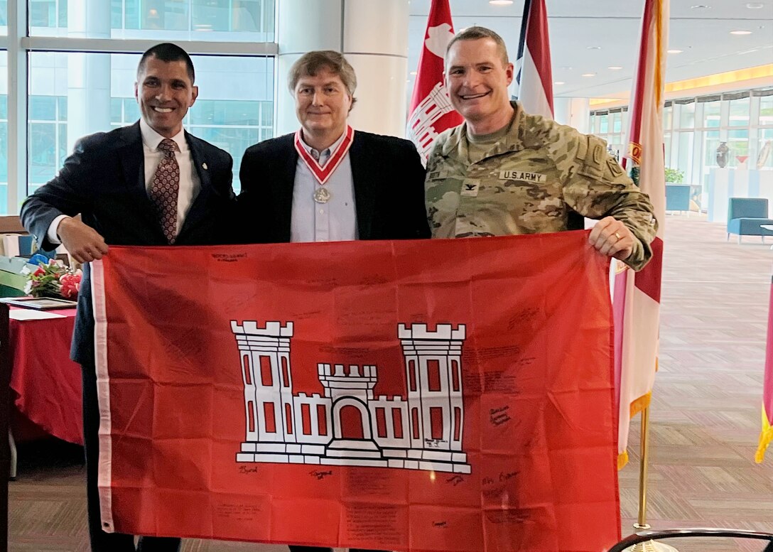(Left to Right) Howie Gonzales, incoming deputy district engineer for Programs and Project Management,  Tim Murphy, outgoing deputy district engineer for Programs and Project Management and Col. James Booth, Jacksonville District Commander hold the U.S. Army Corps of Engineers flag during Murphy's retirement ceremony Dec. 15, 2022 in Jacksonville, Fla.  The flag was presented and signed by district employees.  (USACE Photo by Mark Rankin)