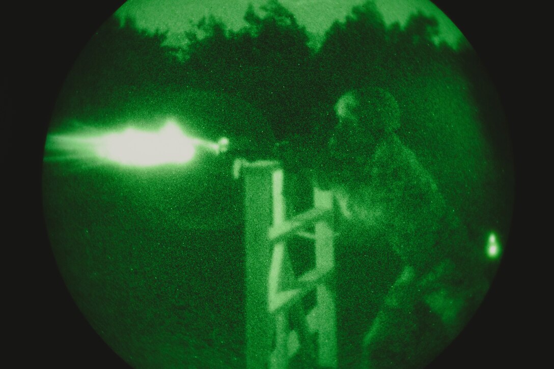 A Marine fires at a target at night.