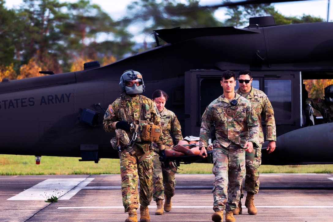 Soldiers carry a stretcher away from a  helicopter.