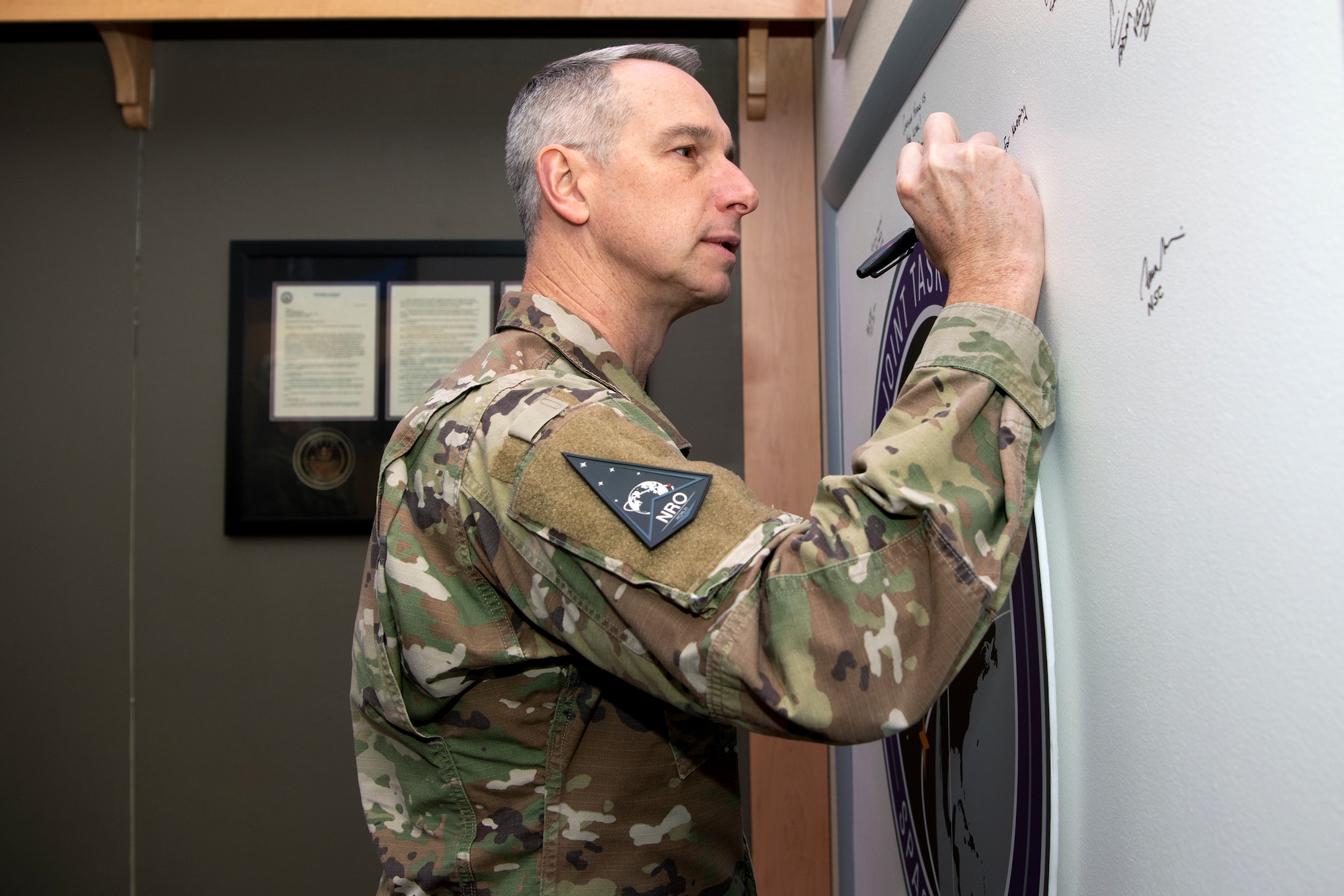 Man in military uniform signing a board