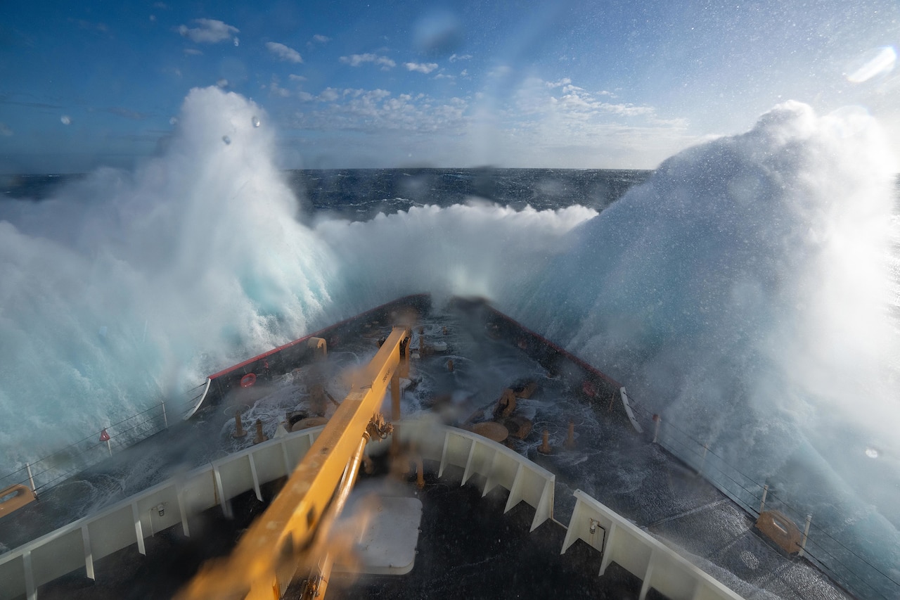 Waves break on the bow of a cutter.
